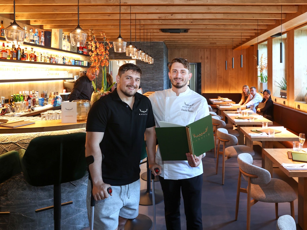 Zwei Männer stehen in einem Restaurant nebeneinsander.
