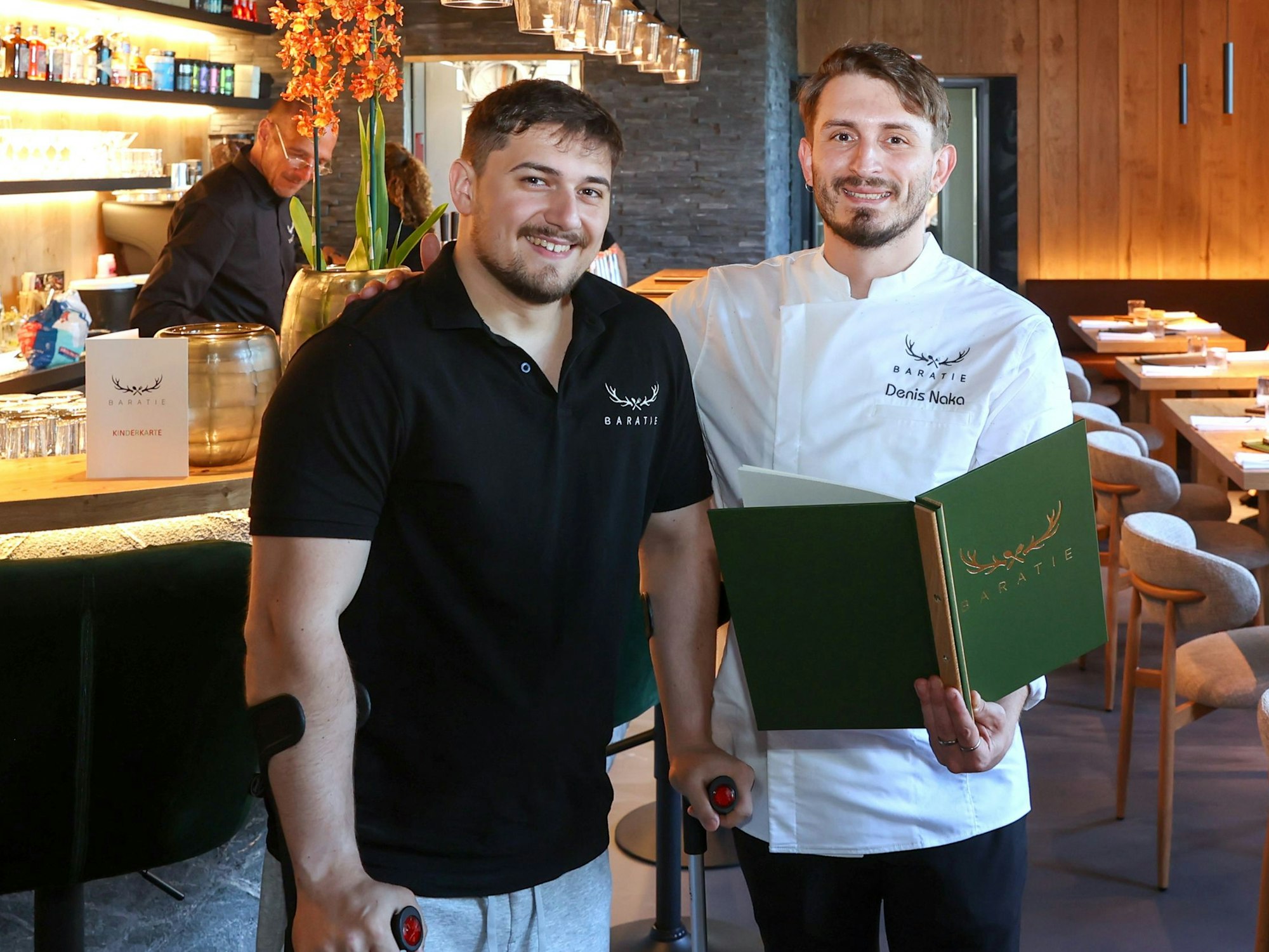 Zwei Männer stehen in einem Restaurant nebeneinsander.