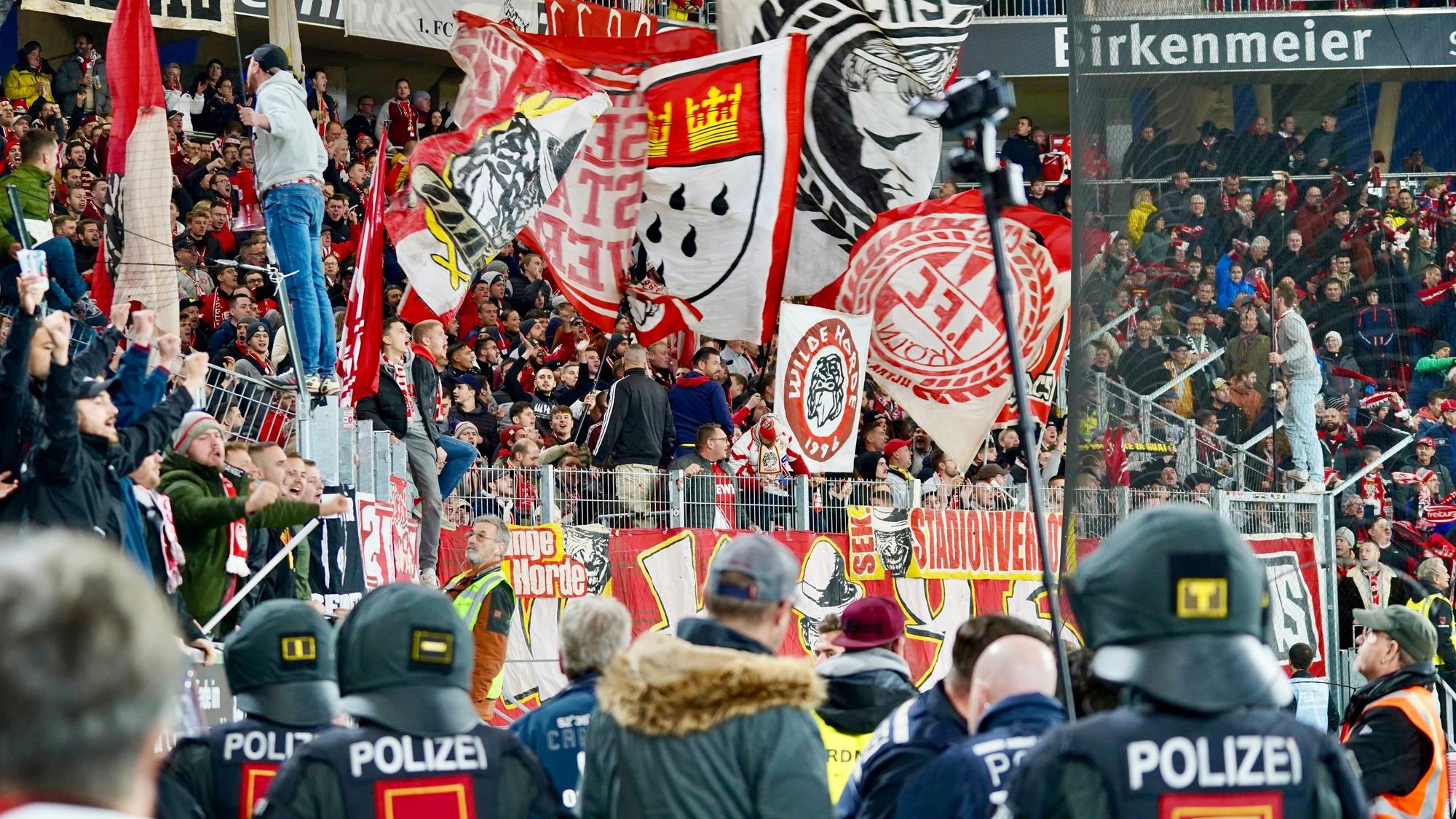 Die Fans des 1. FC Köln beim Spiel gegen den SC Freiburg. Am Zaun hängt ein Banner mit der Aufschrift „Stadionverbot“.