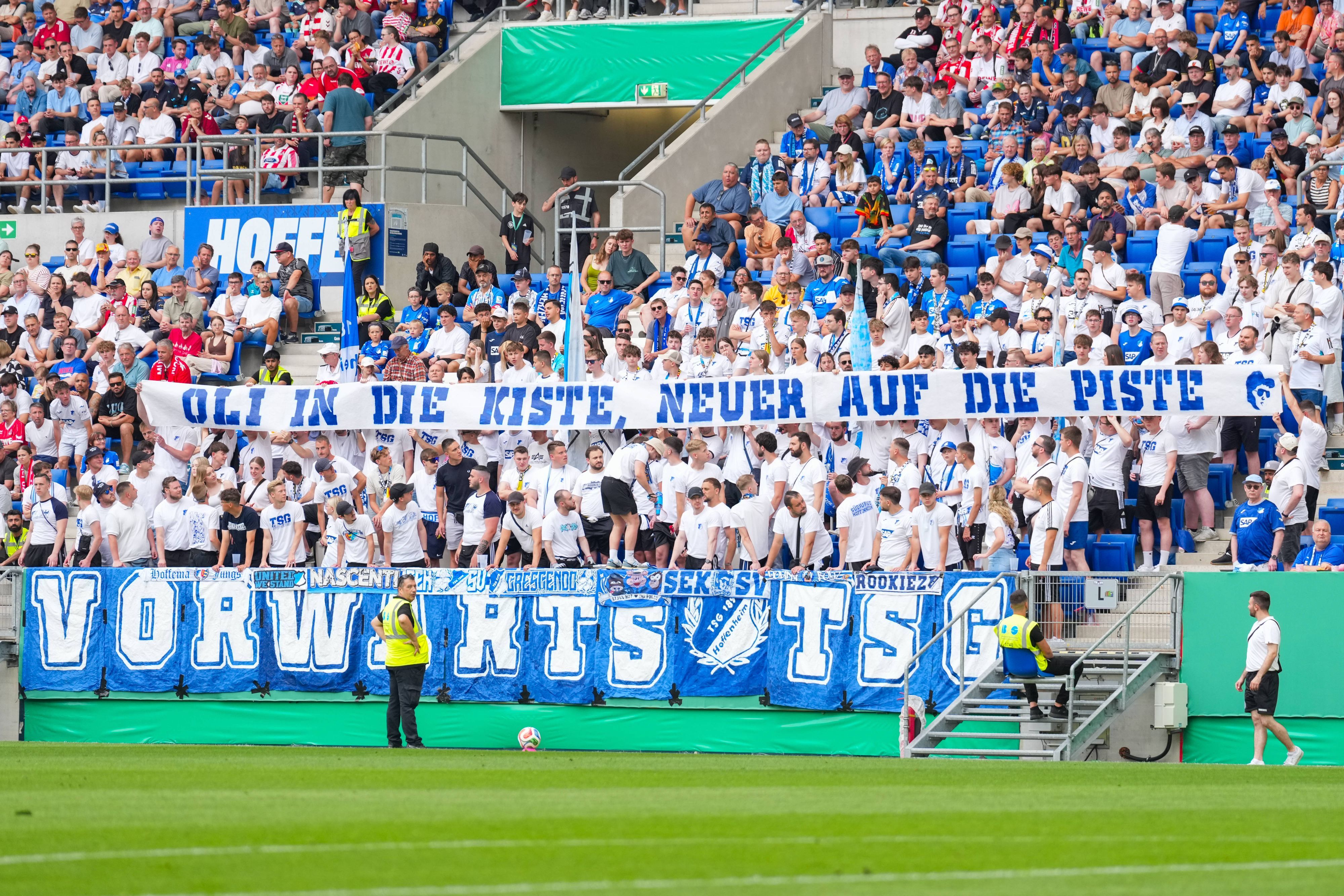 TSG-Fans halten ein Banner auf der Tribüne hoch.