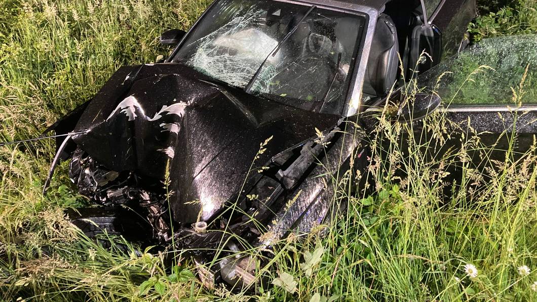 Ein Auto liegt völlig demoliert in einem Grünstreifen.