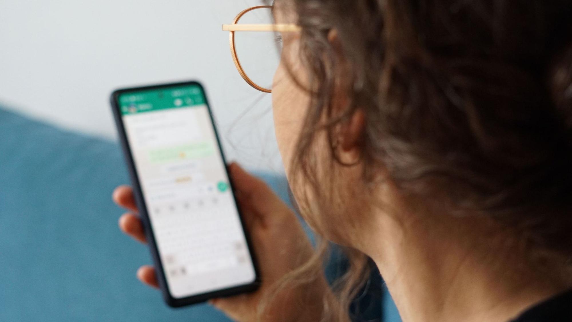 Eine junge Frau liest eine Nachricht auf einem Smartphone