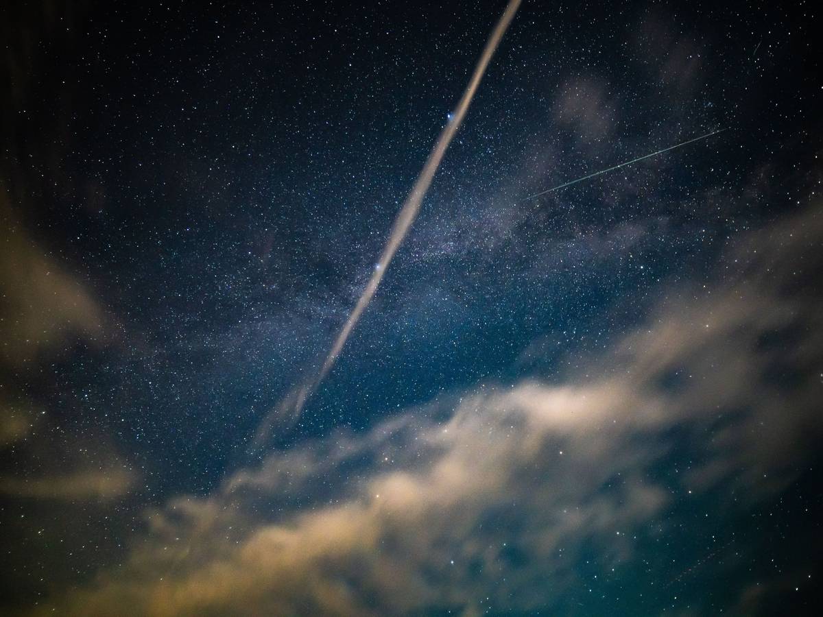 Nachthimmel mit Sternen, Wolken und Lichtspuren