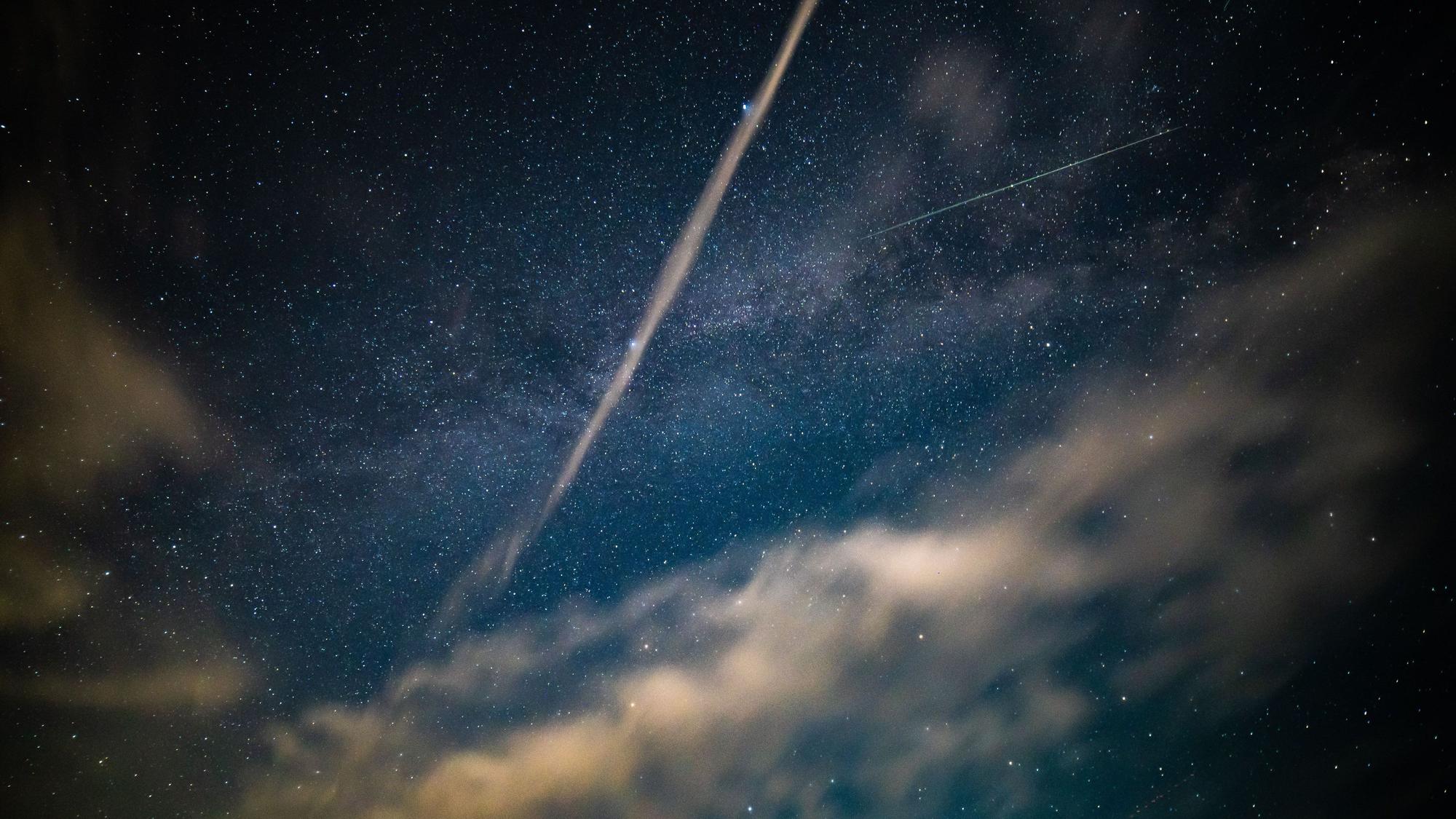 Nachthimmel mit Sternen, Wolken und Lichtspuren