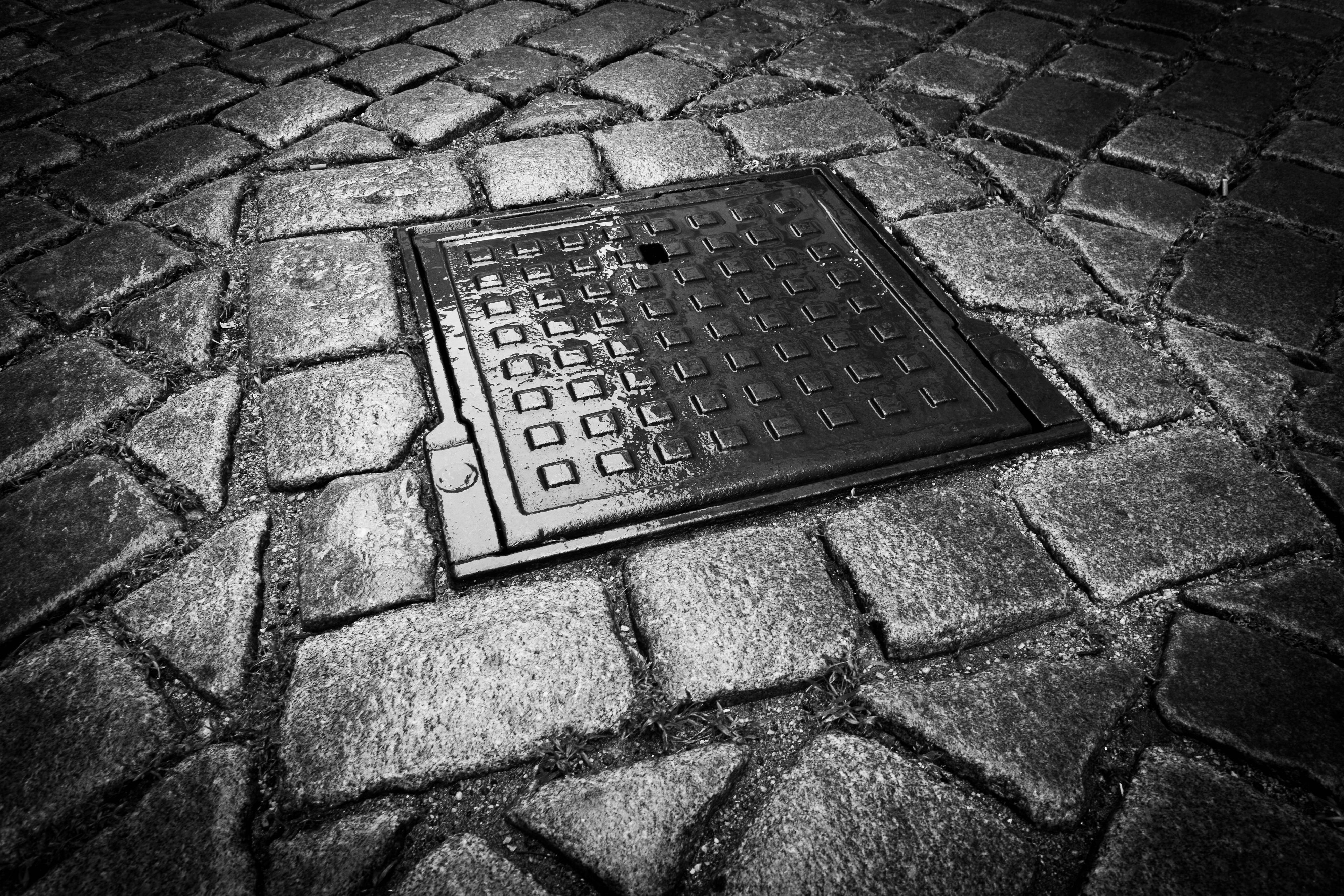 Dunkler Gullydeckel auf Kopfsteinpflaster