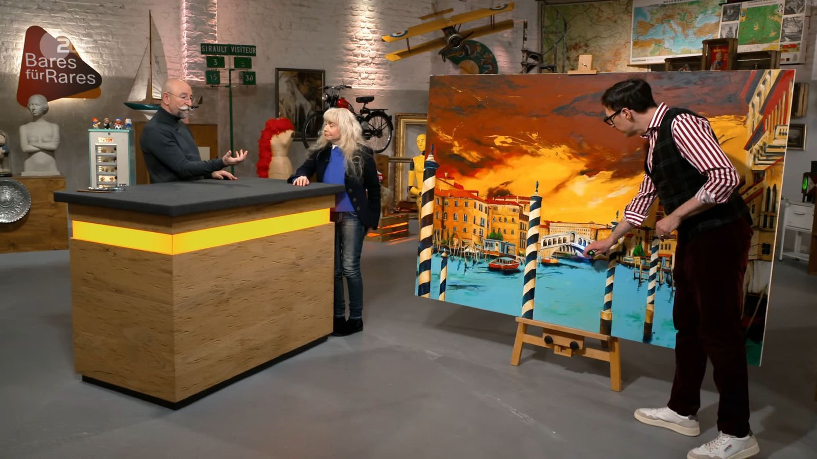 „Oh, wow! Was für ein ausgesprochen farbenfrohes Gemälde!“ So reagierte Horst Lichter (links) auf das „außergewöhnlich große Bild“, das ist seiner Trödelshow vorgestellt wurde. (Bild: ZDF)
