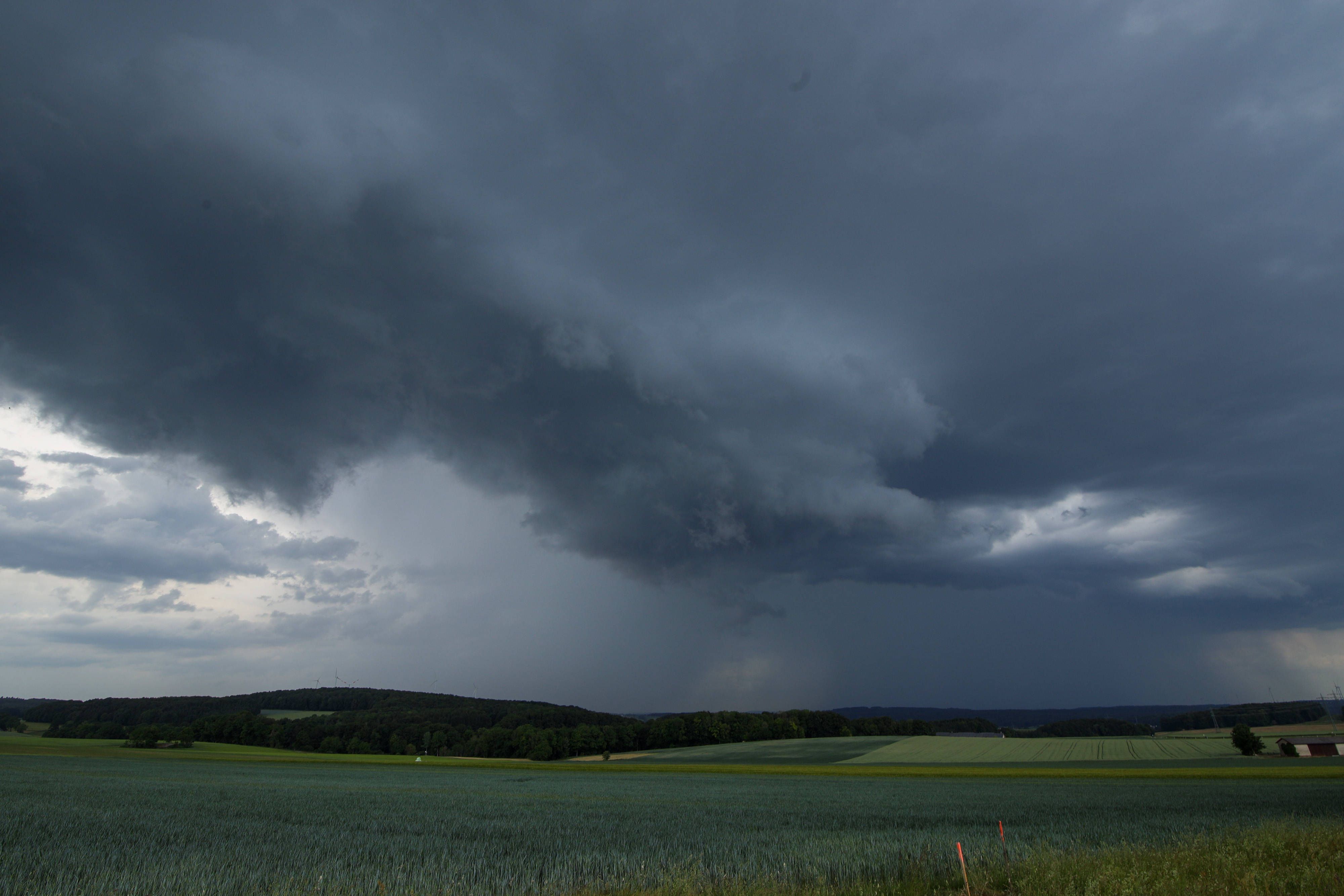 Bedrohliche Gewitterwolken über Feldern und Wald