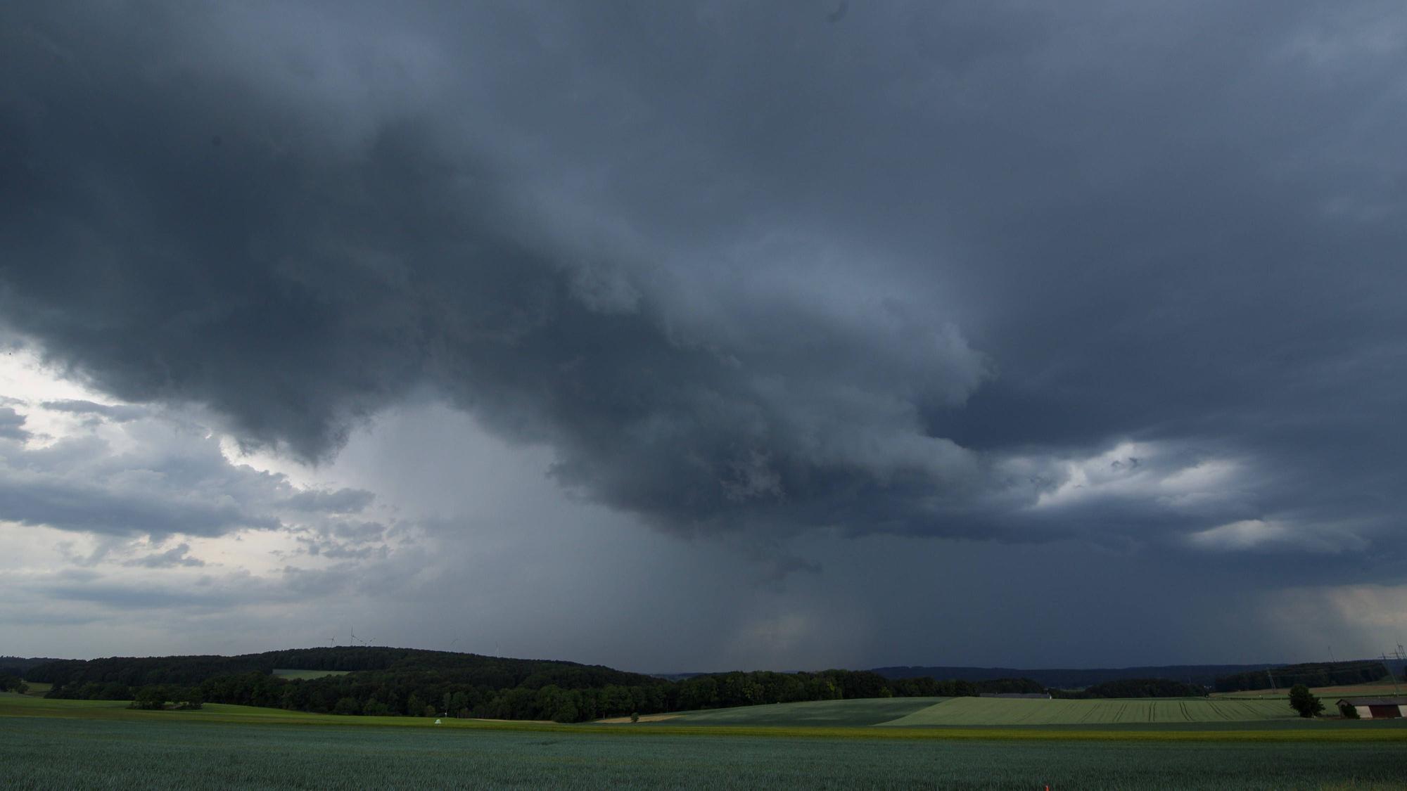 Bedrohliche Gewitterwolken über Feldern und Wald