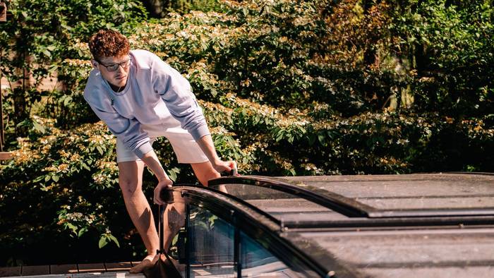 Ein Jugendlicher öffnet eine Poolabdeckung