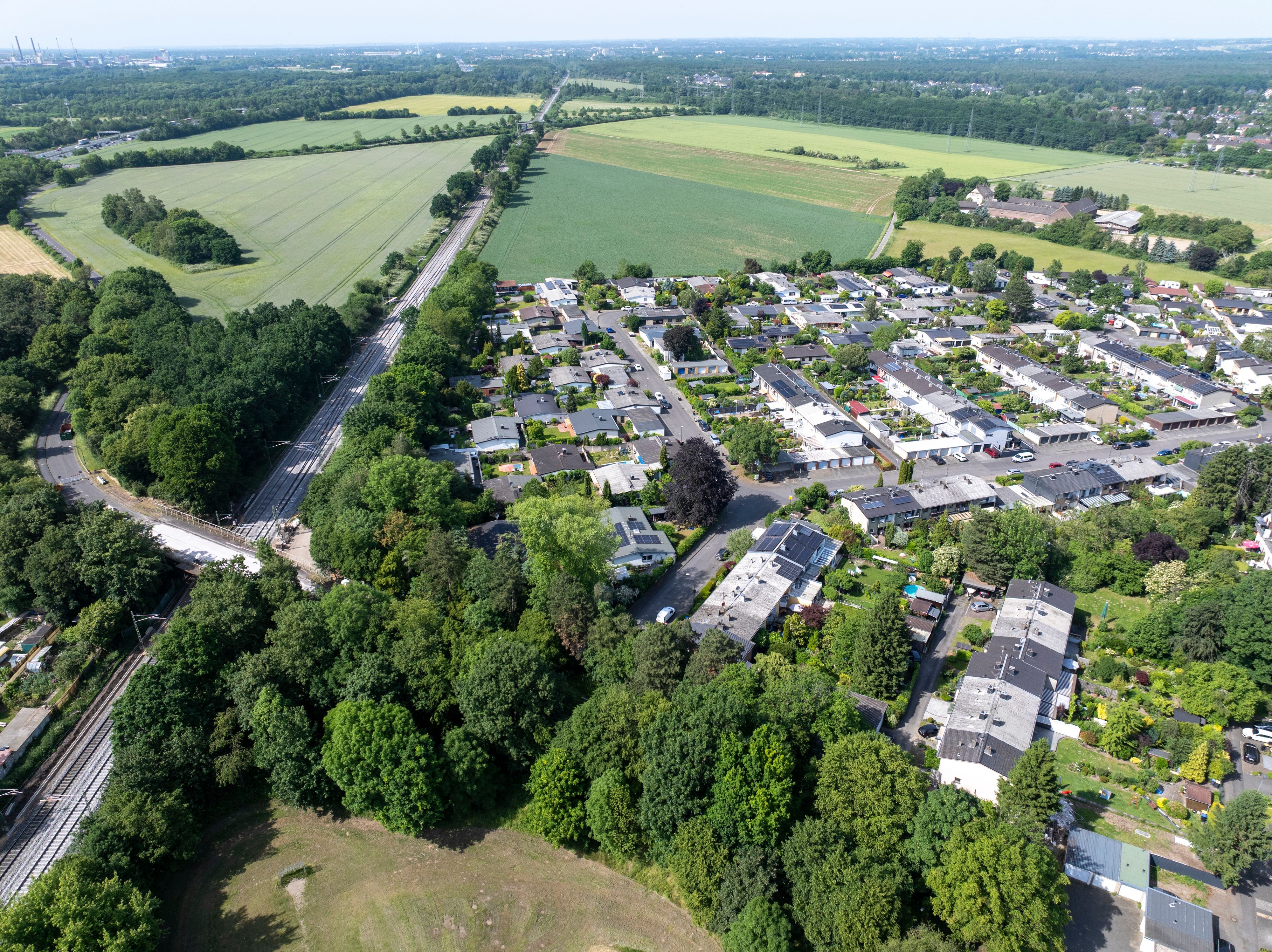 Die Siedlung Schönrath liegt inmitten von Grün, linkerhand führt eine Straße entlang.