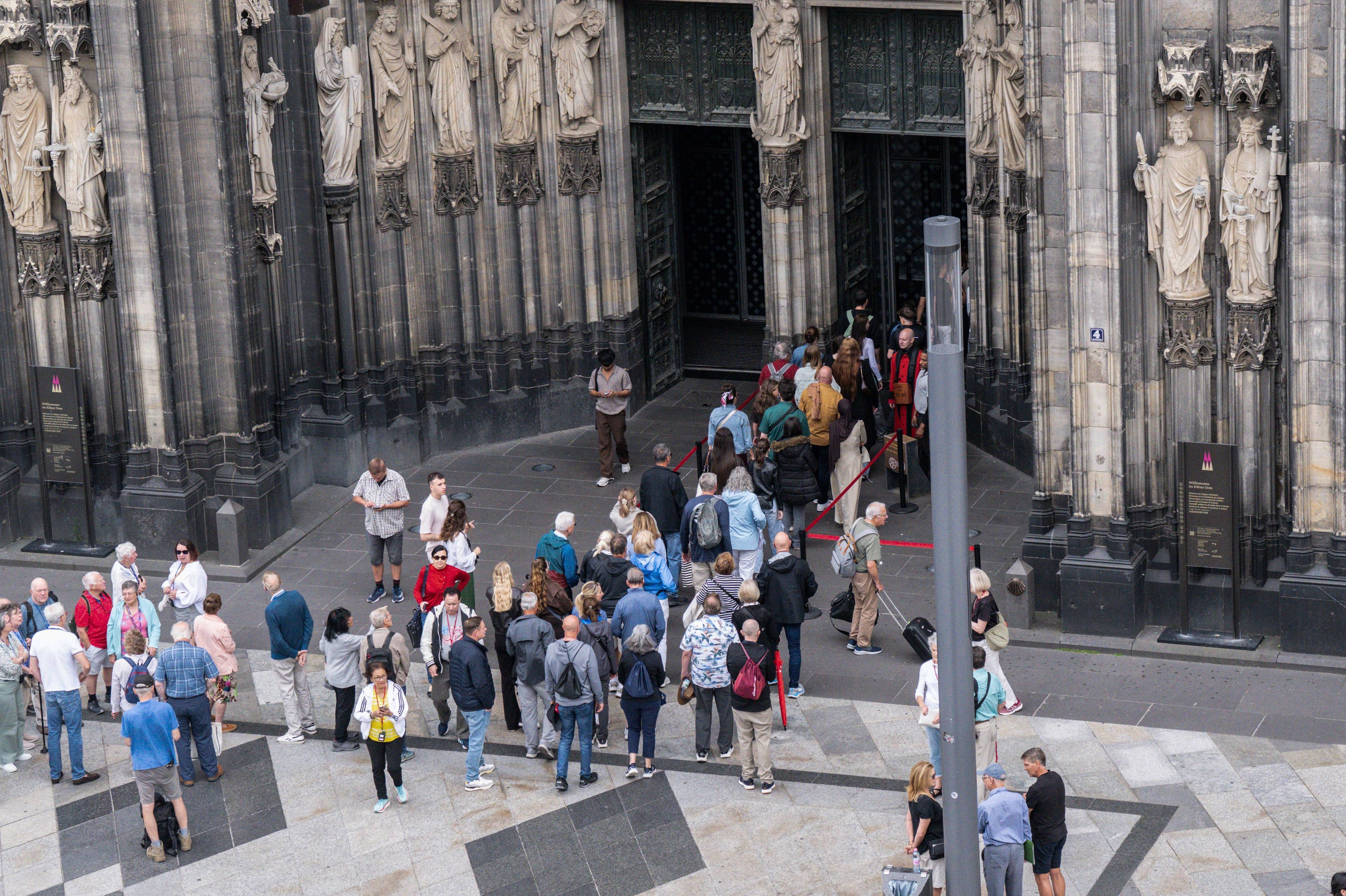 Besucher stehen vor dem Dom in Köln Schlange.