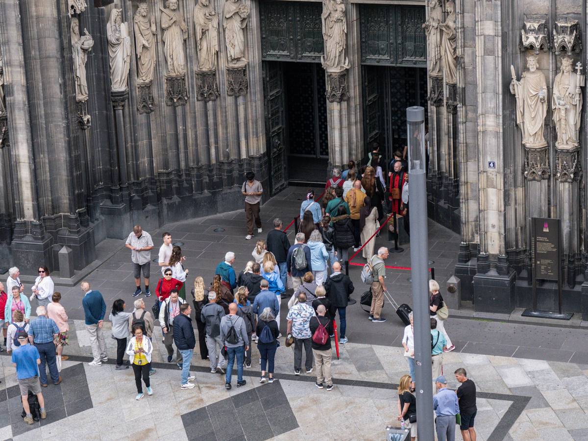 Besucher stehen vor dem Dom in Köln Schlange.