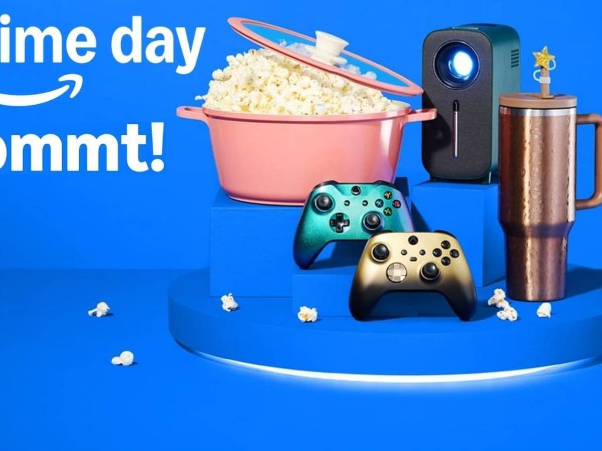 Ankündigungsbild zum Amazon Prime Day 2026 auf blauem Hintergrund mit dem Amazon-Logo und dem Schriftzug "prime day kommt!". Im Vordergrund sind verschiedene Produkte arrangiert: ein rosafarbener Kochtopf gefüllt mit Popcorn, ein kompakter Beamer, zwei Xbox-Controller in Gold und Grün-Metallic sowie ein kupferfarbener Thermobecher.