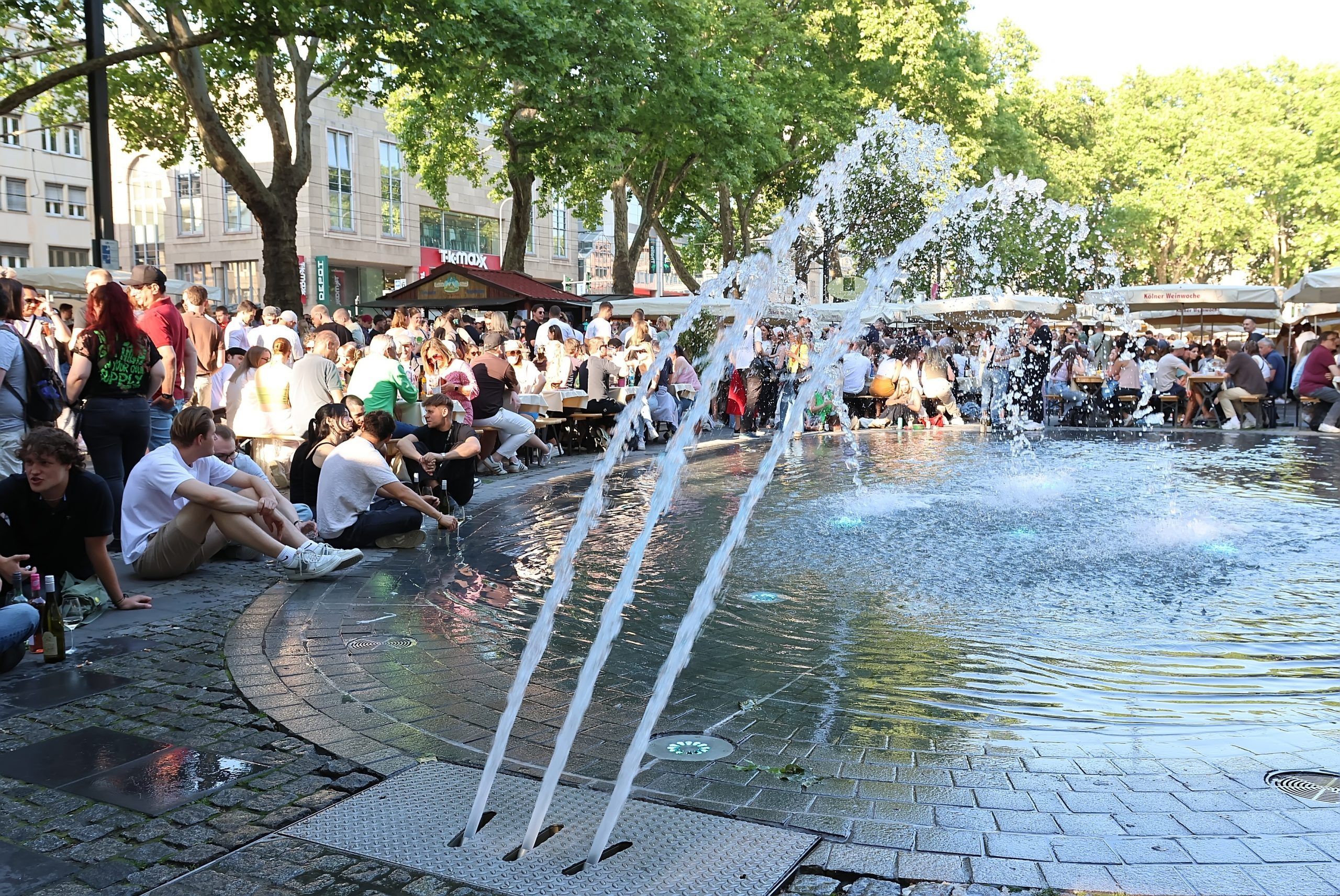 Eine Menschenmenge sitzt um den Brunnen auf dem Neumarkt.