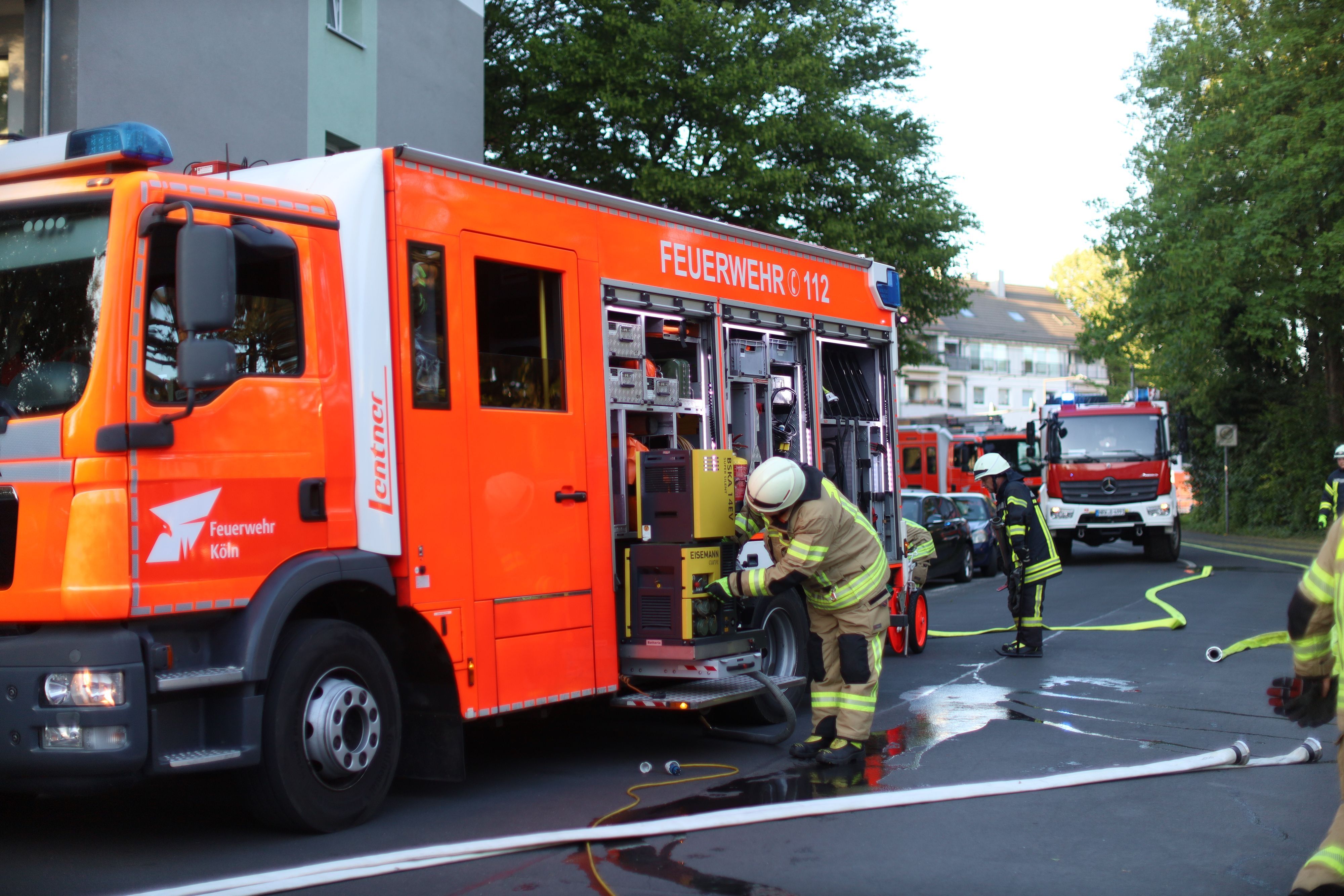 Mehrere Fahrzeuge der Feuerwehr stehen in einer Straße, mehrere Wehrmänner sind im Einsatz.
