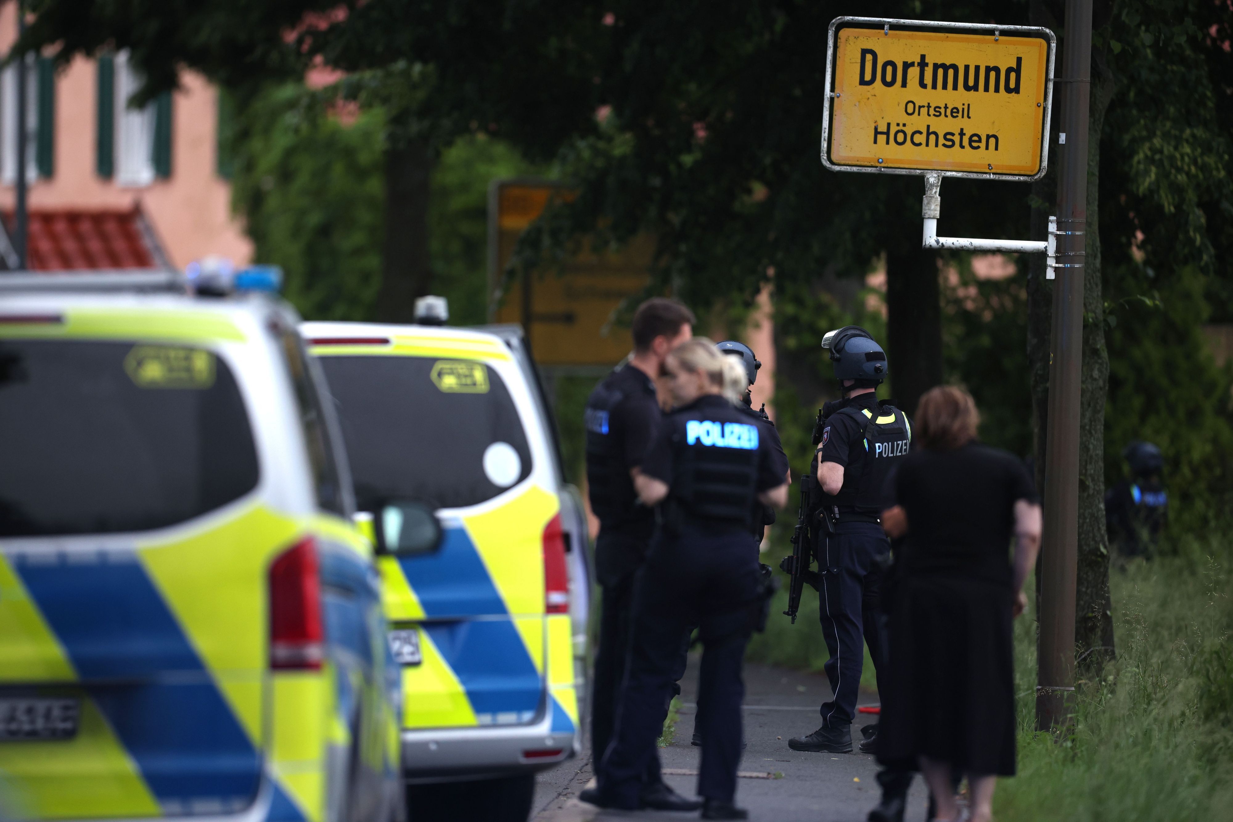 Mehrere Polizisten und Polizeiwagen stehen an einer Straße.