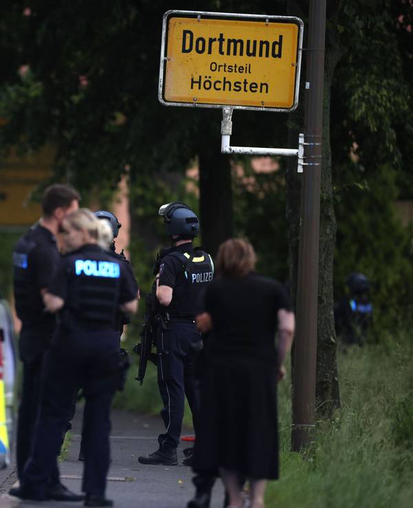 Mehrere Polizisten und Polizeiwagen stehen an einer Straße.