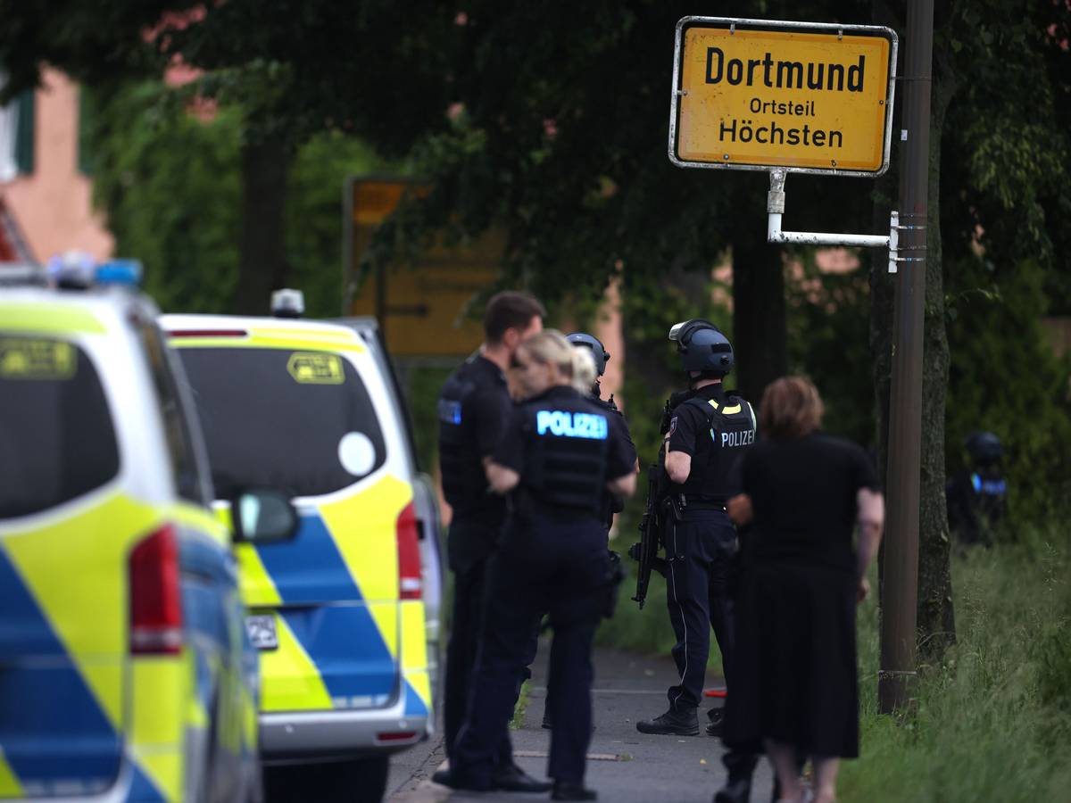 Mehrere Polizisten und Polizeiwagen stehen an einer Straße.