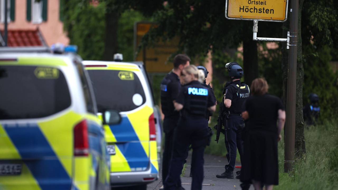 Mehrere Polizisten und Polizeiwagen stehen an einer Straße.
