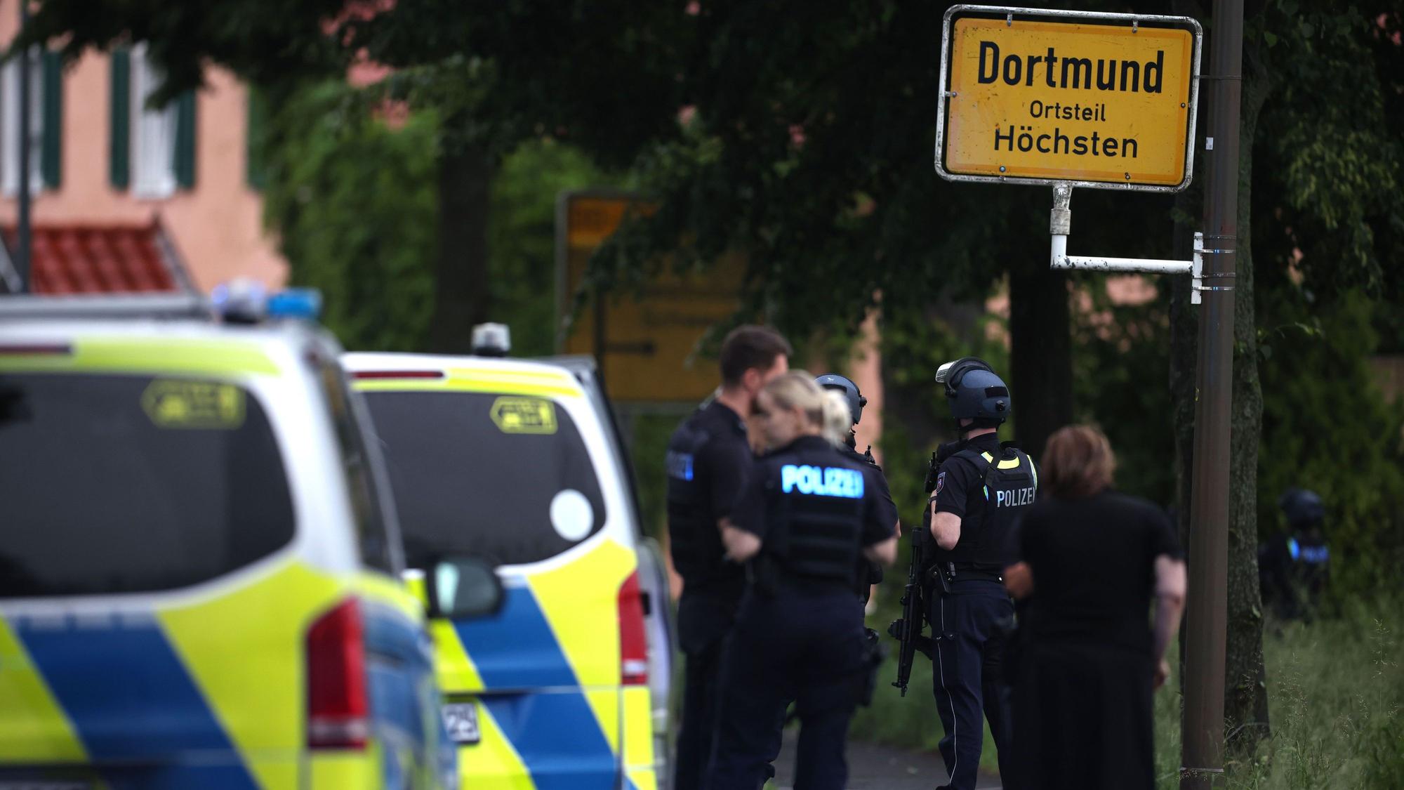Mehrere Polizisten und Polizeiwagen stehen an einer Straße.
