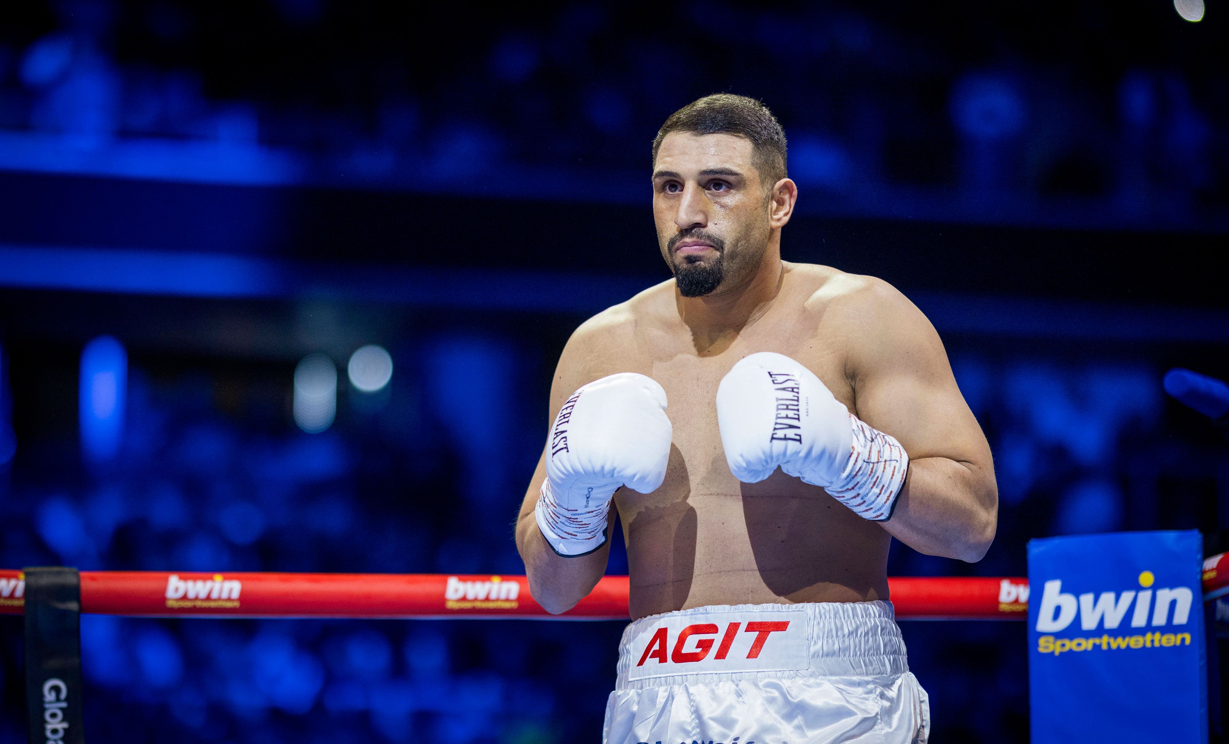 Agit Kabayel steht im Ring und trägt weiße Boxhandschuhe.