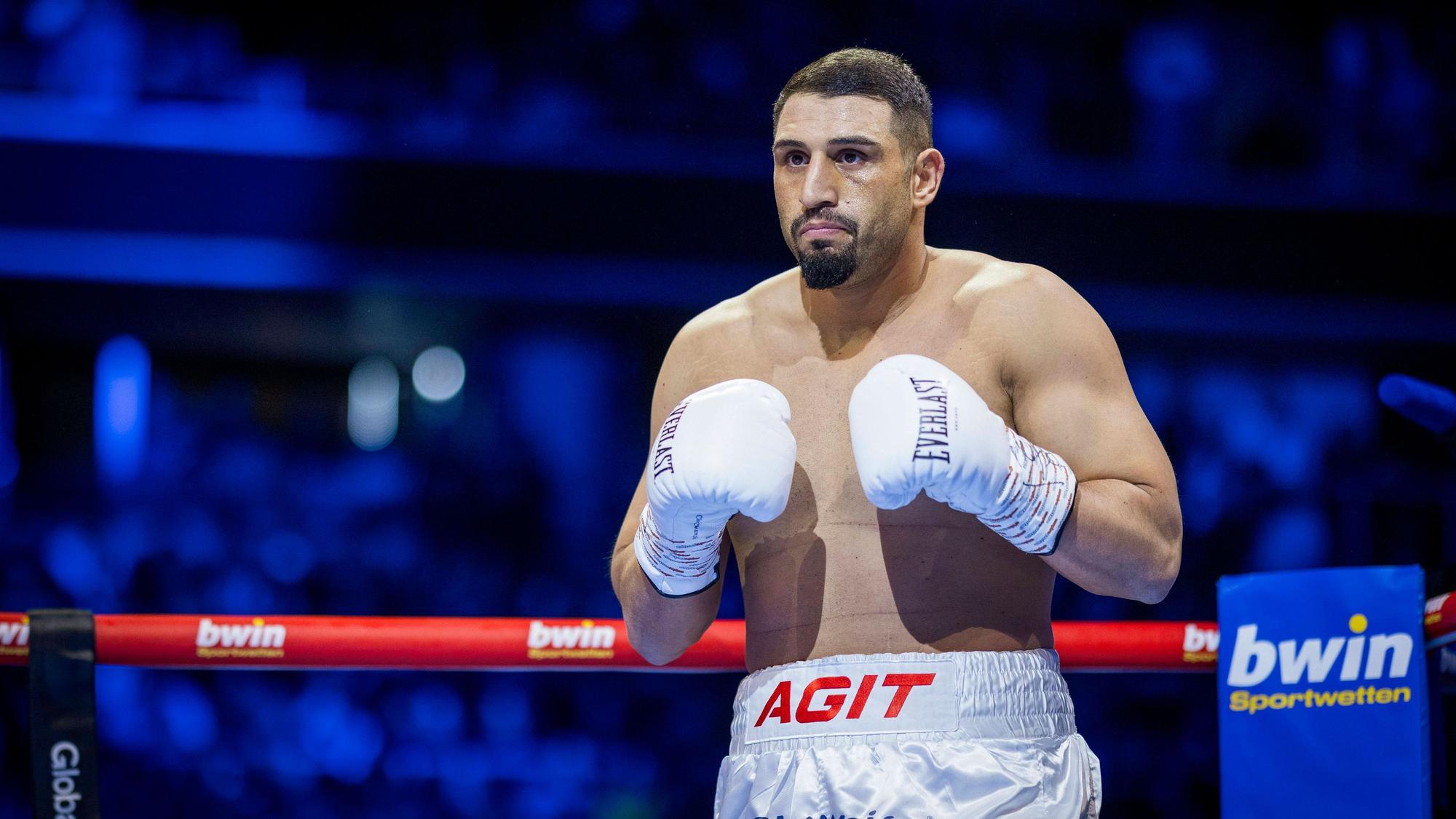Agit Kabayel steht im Ring und trägt weiße Boxhandschuhe.