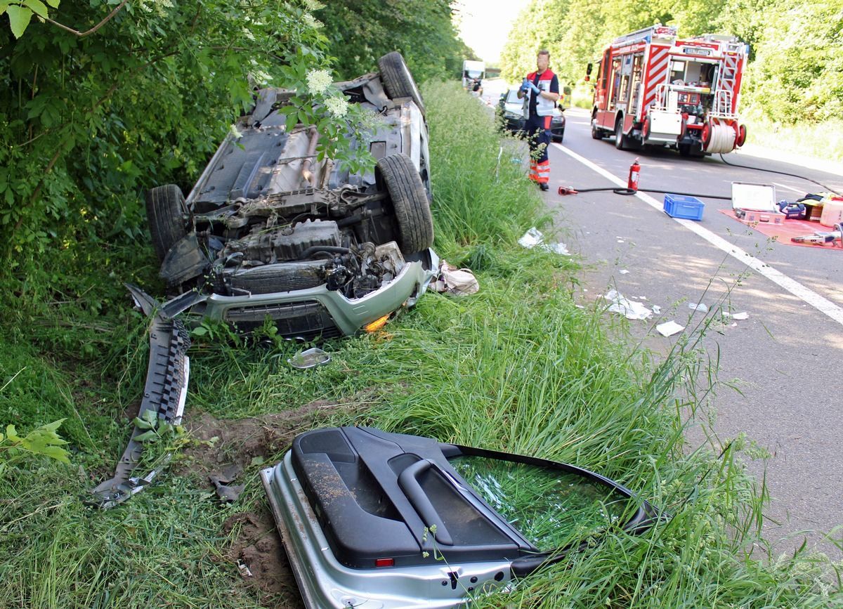 Ein demoliertes Auto liegt nach einem Unfall auf der Seite im Grünstreifen.