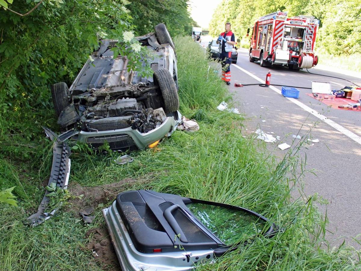 Ein demoliertes Auto liegt nach einem Unfall auf der Seite im Grünstreifen.