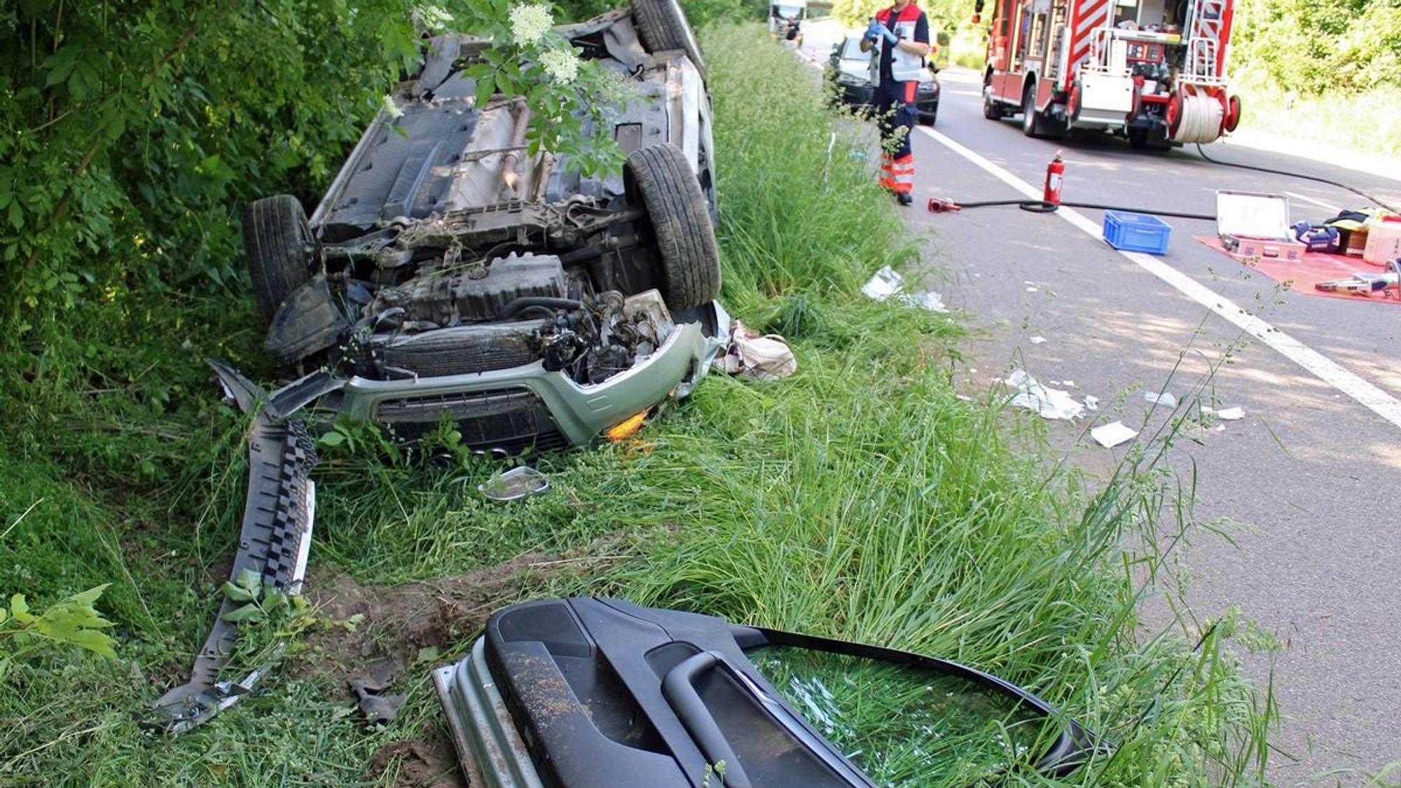 Ein demoliertes Auto liegt nach einem Unfall auf der Seite im Grünstreifen.