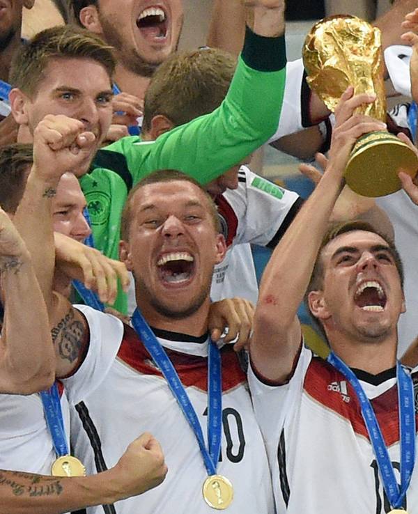 Philipp Lahm (M) jubelt mit dem WM-Pokal zwischen seinen Teamkollegen Lukas Podolski (l) und Thomas Müller (r) während der Siegerehrung auf der Tribüne nach dem Finalsieg gegen Argentinien im Estadio do Maracana.
