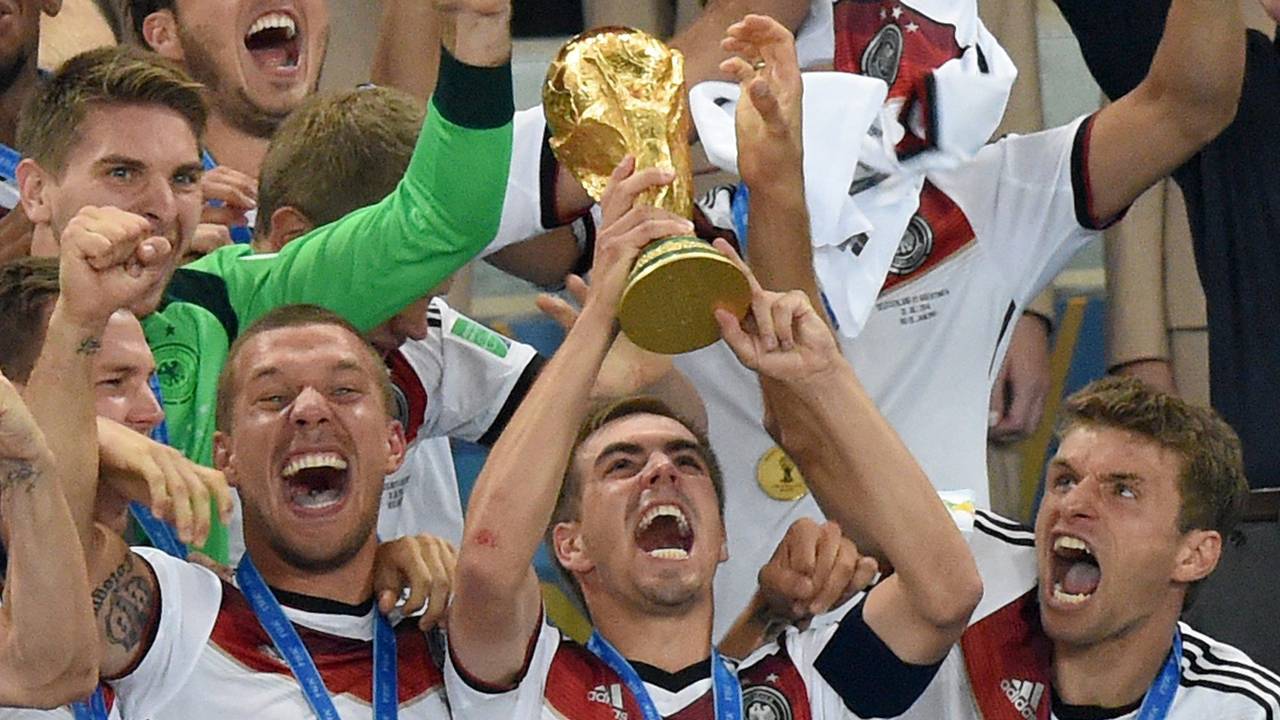 Philipp Lahm (M) jubelt mit dem WM-Pokal zwischen seinen Teamkollegen Lukas Podolski (l) und Thomas Müller (r) während der Siegerehrung auf der Tribüne nach dem Finalsieg gegen Argentinien im Estadio do Maracana.