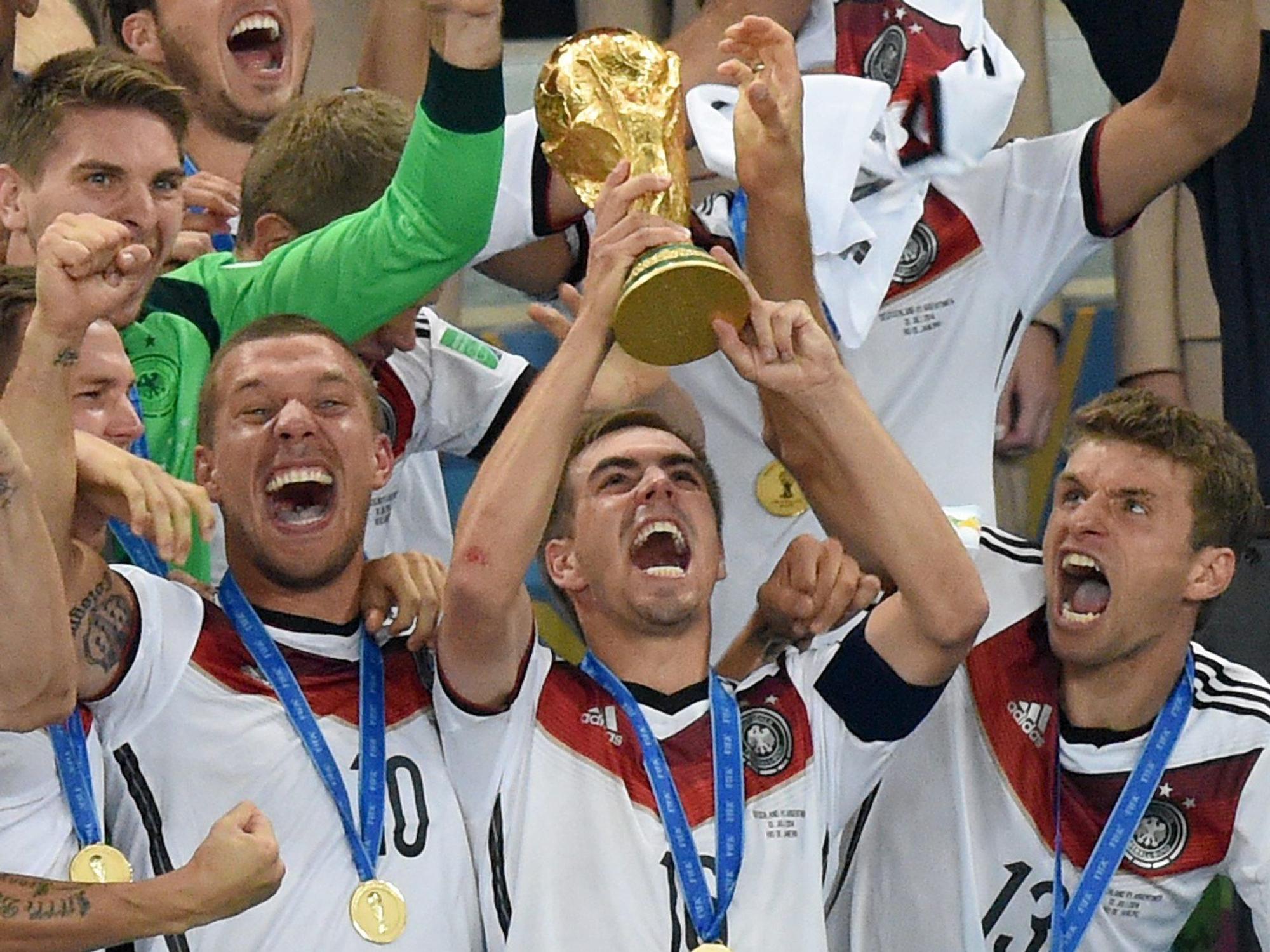 Philipp Lahm (M) jubelt mit dem WM-Pokal zwischen seinen Teamkollegen Lukas Podolski (l) und Thomas Müller (r) während der Siegerehrung auf der Tribüne nach dem Finalsieg gegen Argentinien im Estadio do Maracana.