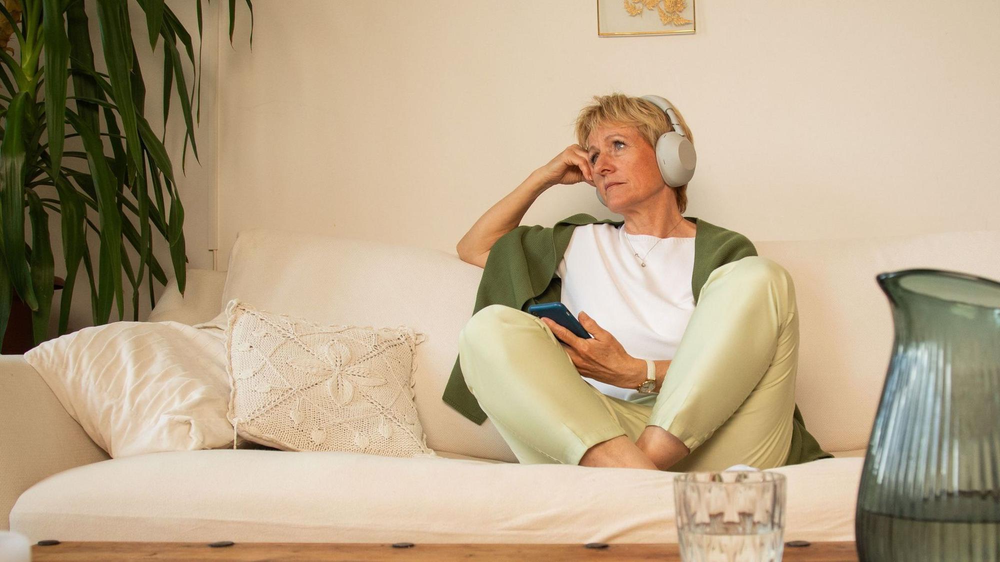 Eine Frau sitzt nachdenklich auf einem Sofa