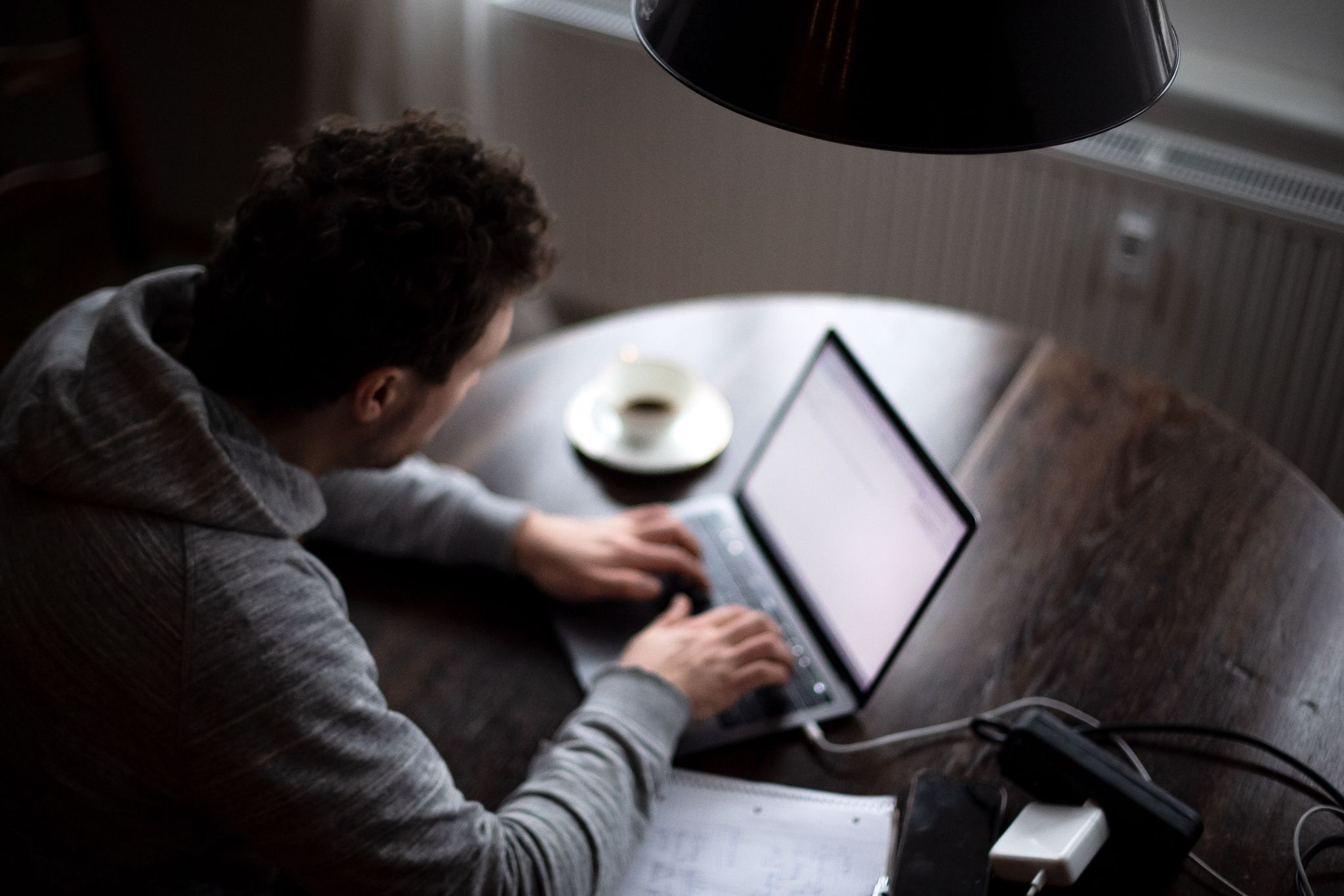 Ein Mann sitzt mit Laptop am Küchentisch