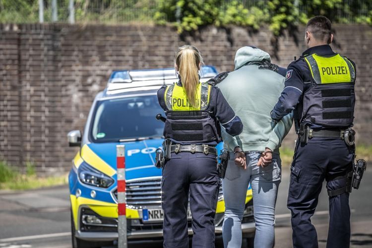 Zwei Männer werden von Polizisten abgeführt.