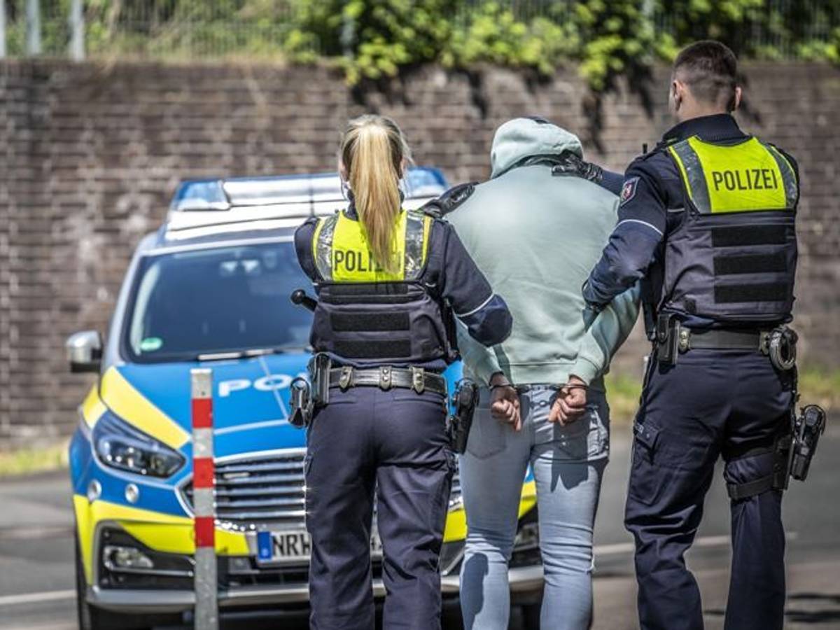 Zwei Männer werden von Polizisten abgeführt.