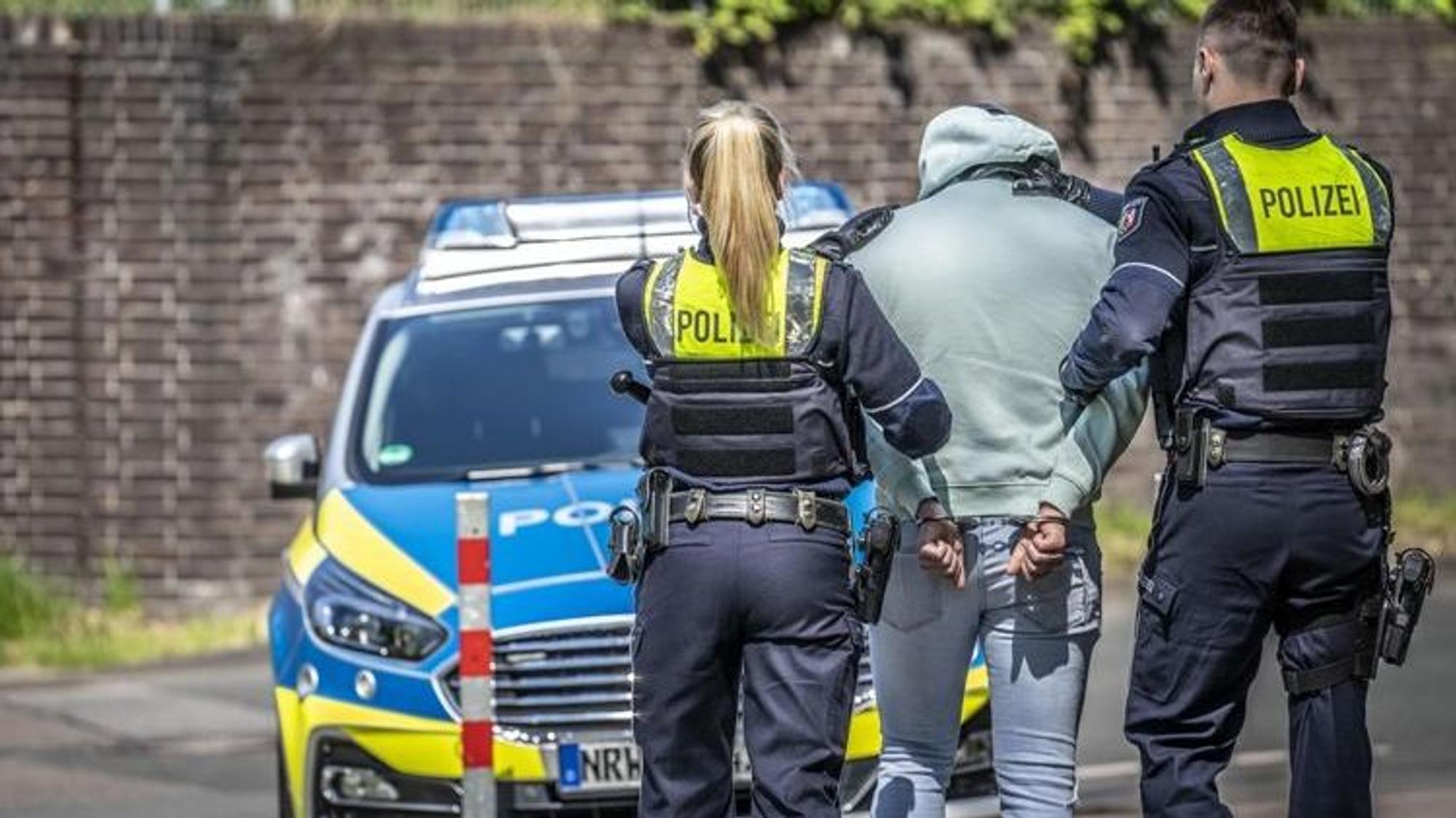 Zwei Männer werden von Polizisten abgeführt.