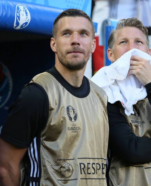 Lukas Podolski und Bastian Schweinsteiger stehen als Ersatzspieler vor der Bank.