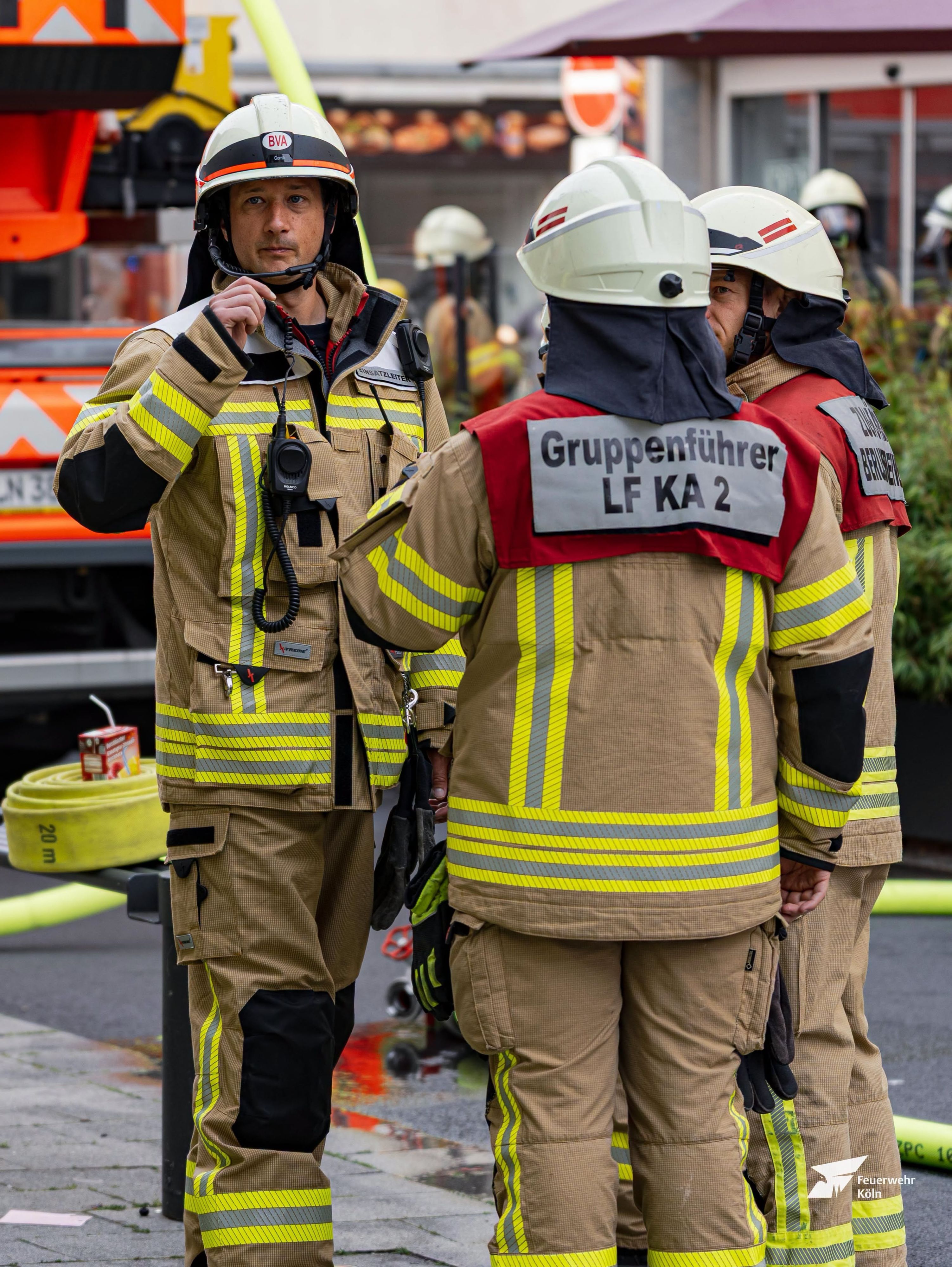 Einsatzkräfte der Kölner Feuerwehr stehen an einem Brandort.