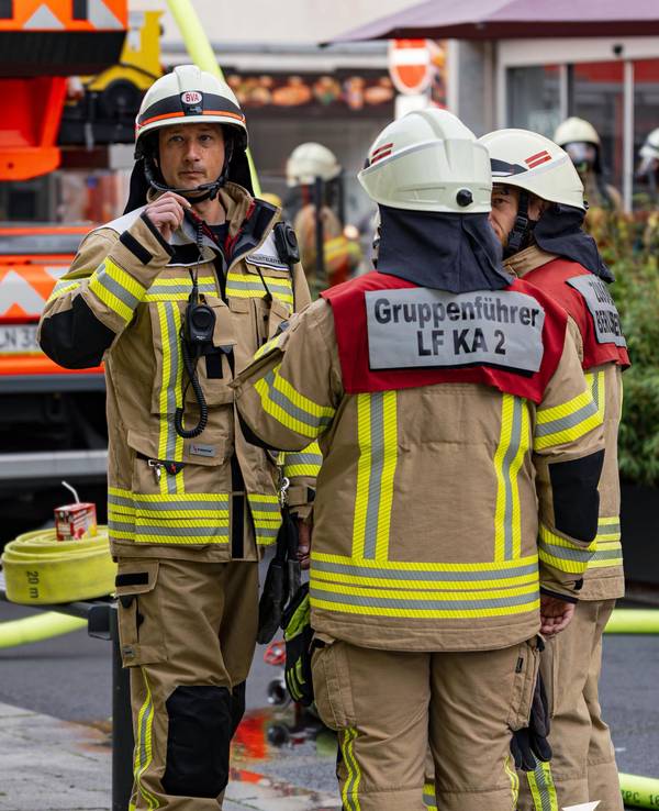 Einsatzkräfte der Kölner Feuerwehr stehen an einem Brandort.