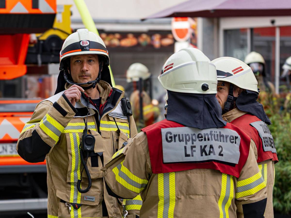 Einsatzkräfte der Kölner Feuerwehr stehen an einem Brandort.