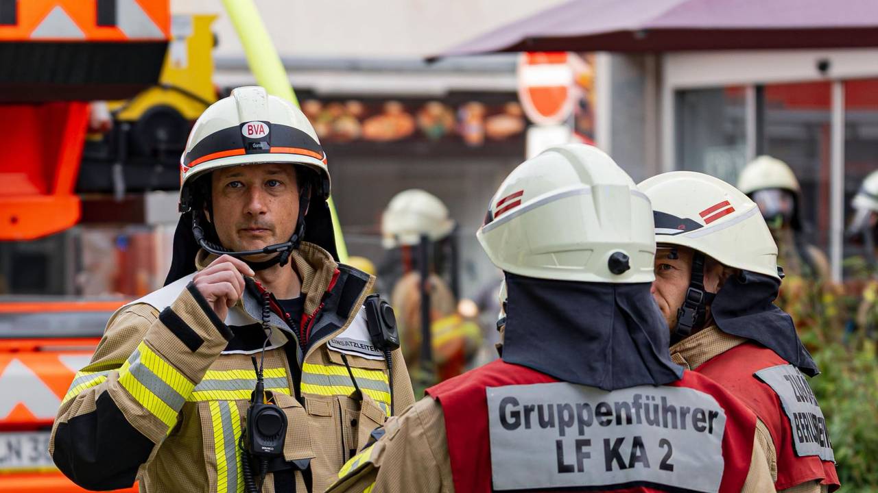 Einsatzkräfte der Kölner Feuerwehr stehen an einem Brandort.