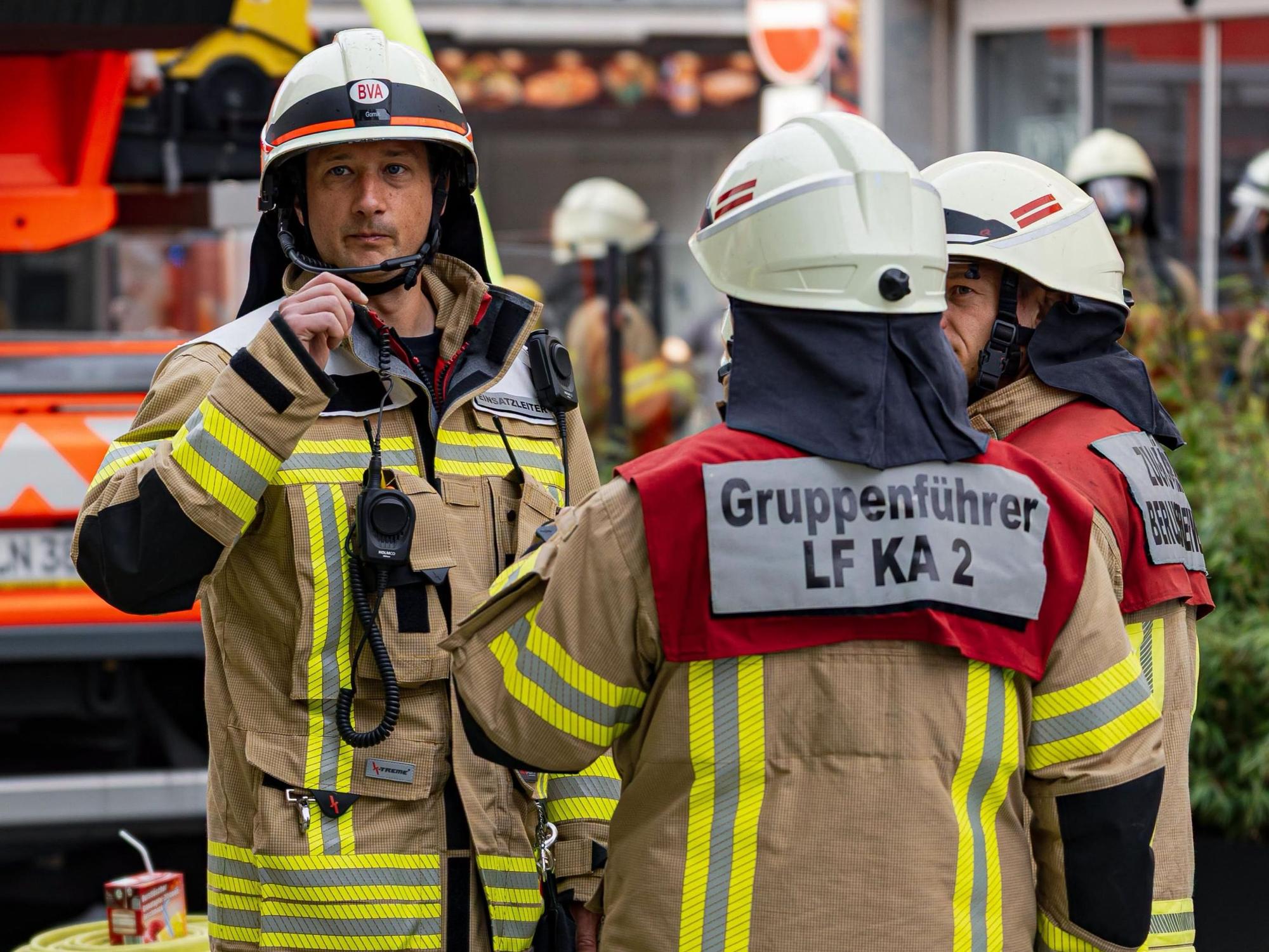 Einsatzkräfte der Kölner Feuerwehr stehen an einem Brandort.