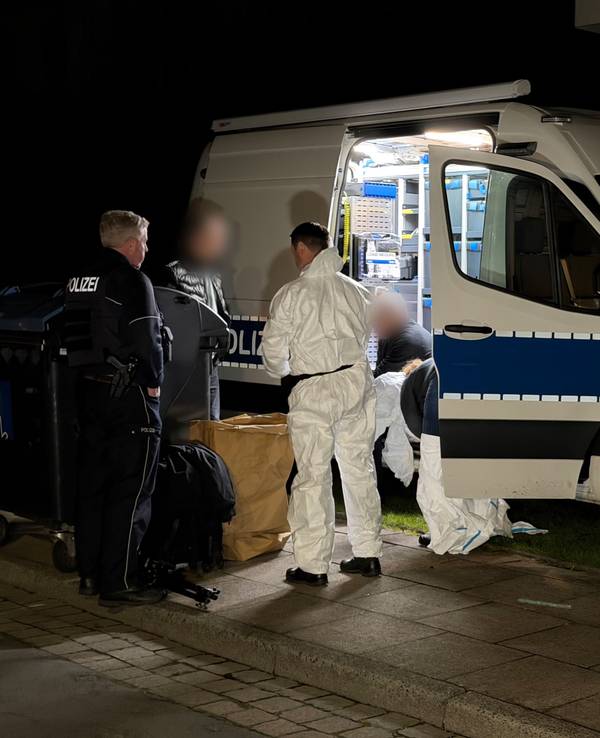 Kräfte von Polizei und Spurensicherung besprechen sich an einem Einsatzfahrzeug.