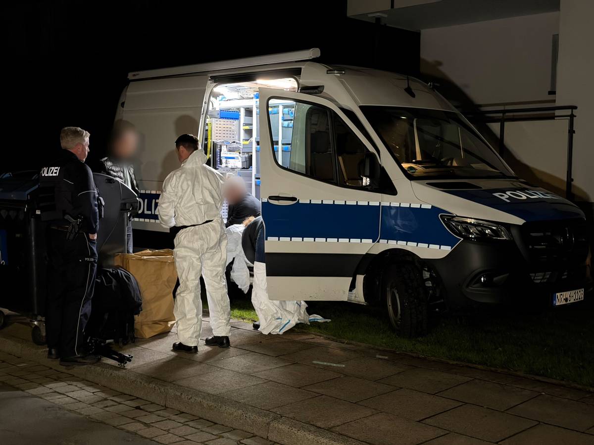 Kräfte von Polizei und Spurensicherung besprechen sich an einem Einsatzfahrzeug.