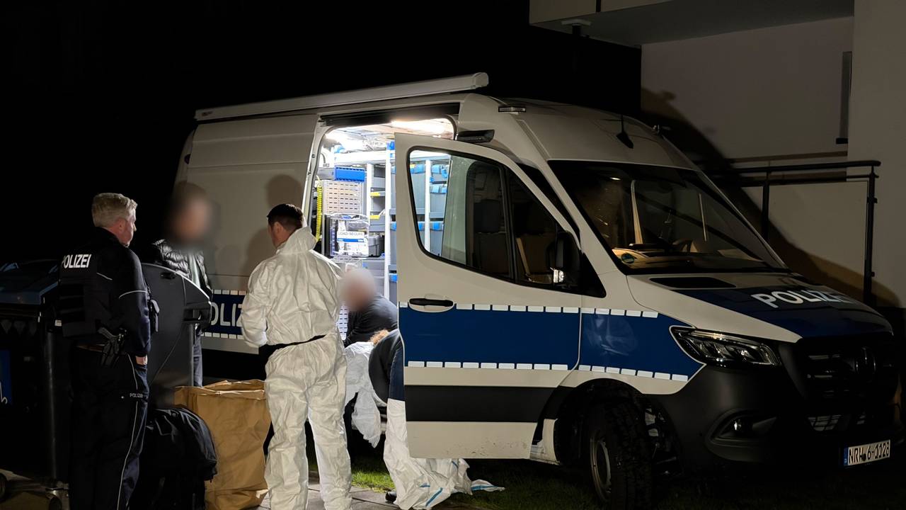 Kräfte von Polizei und Spurensicherung besprechen sich an einem Einsatzfahrzeug.