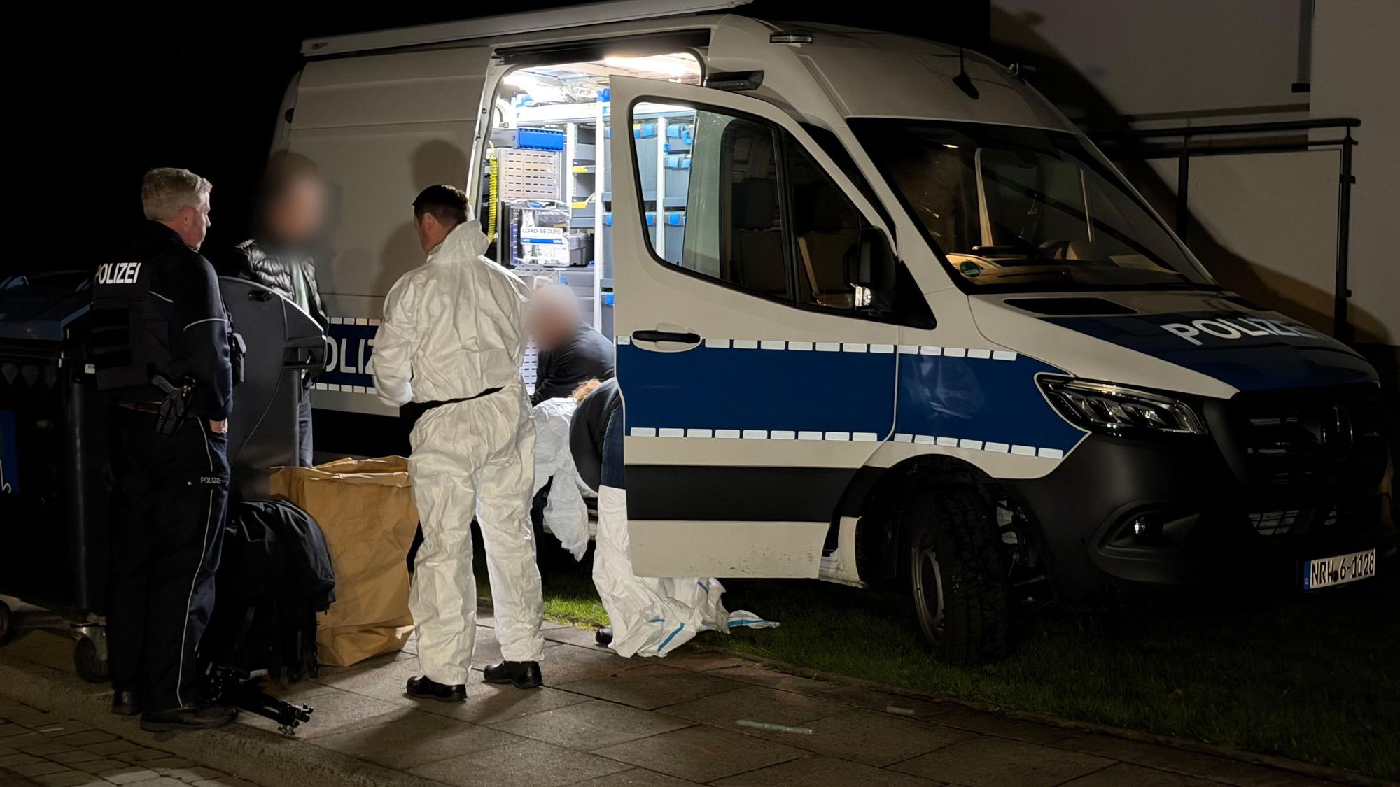 Kräfte von Polizei und Spurensicherung besprechen sich an einem Einsatzfahrzeug.