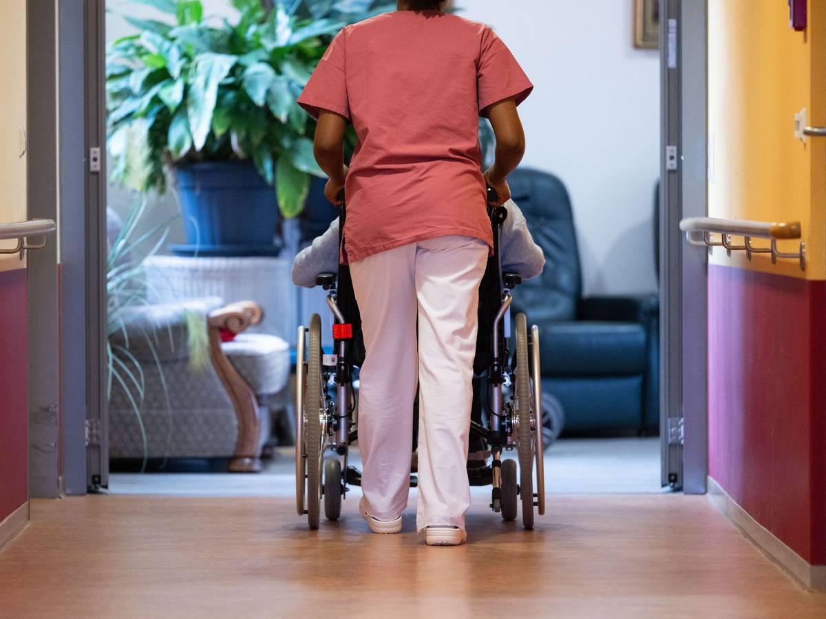 Eine Pflegekraft schiebt einen Pflegebedürftigen im Rollstuhl