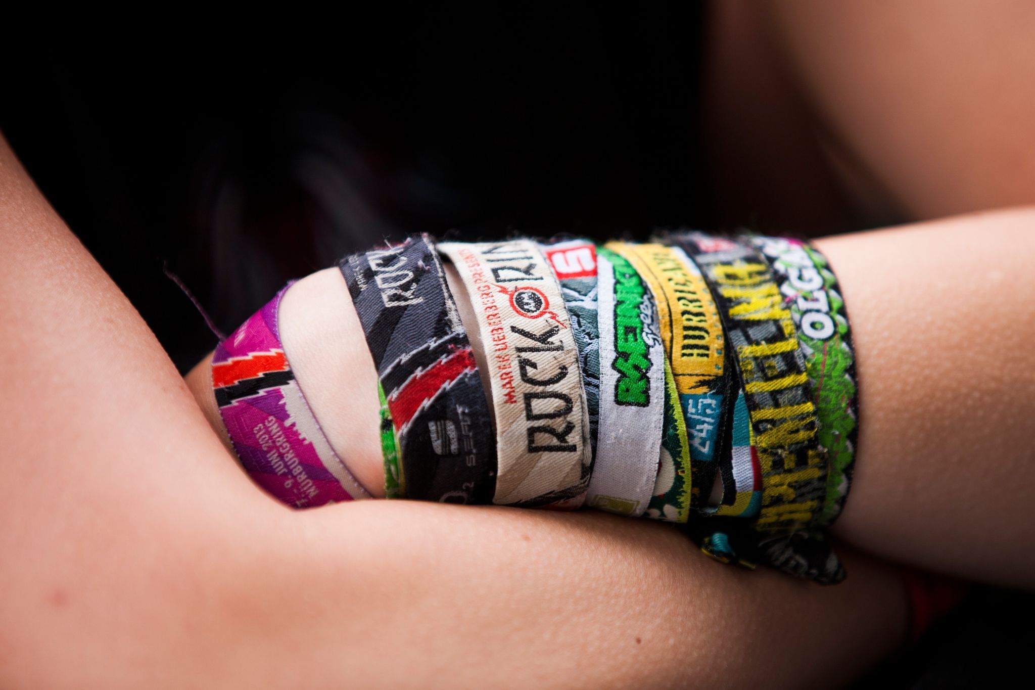 Ein Festival-Fan mit verschiedenen Bändchen verschränkt die Arme