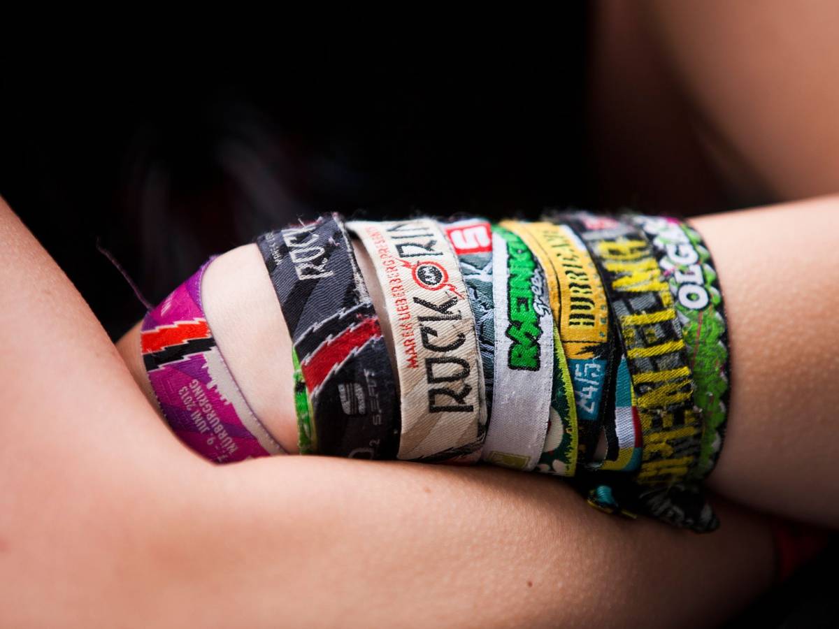 Ein Festival-Fan mit verschiedenen Bändchen verschränkt die Arme